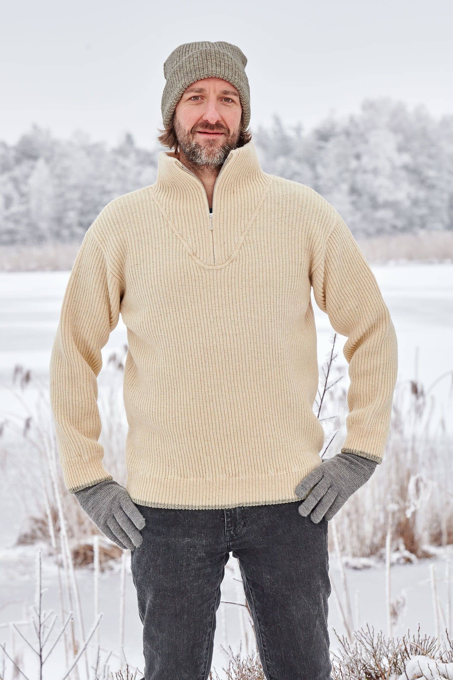 Mann in Schneelandschaft trögt einen naturweißen Finkhof Troyer aus bio Wolle (kbT)