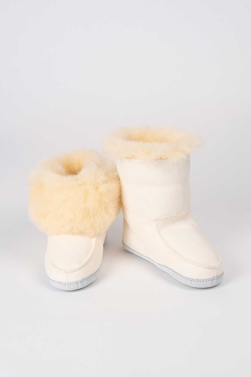 Ein Paar weiße Finkhof-Fellschuhe aus Schaffell und Rindsleder, wobei bei einem der Schaft nach oben geklappt ist