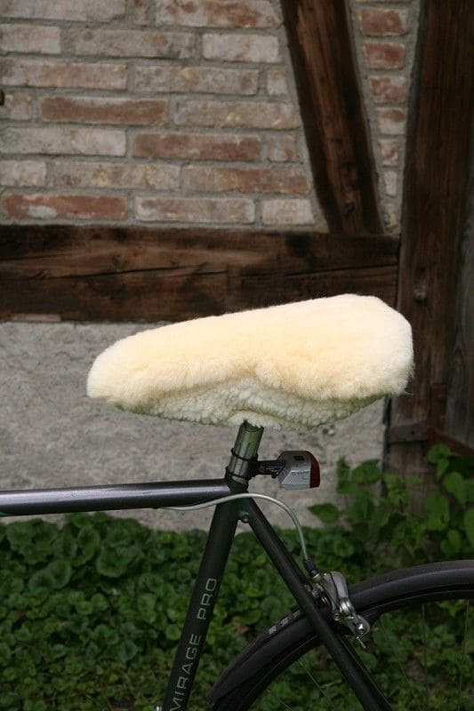 Fahrradsattelbezug relugan-gegerbt schmal schmaler relugan gegerbter Finkhof Sattelbezug aus bio Wolle (kbT) und Schaffell auf Fahrrad mit Steinwand im Hintergrund