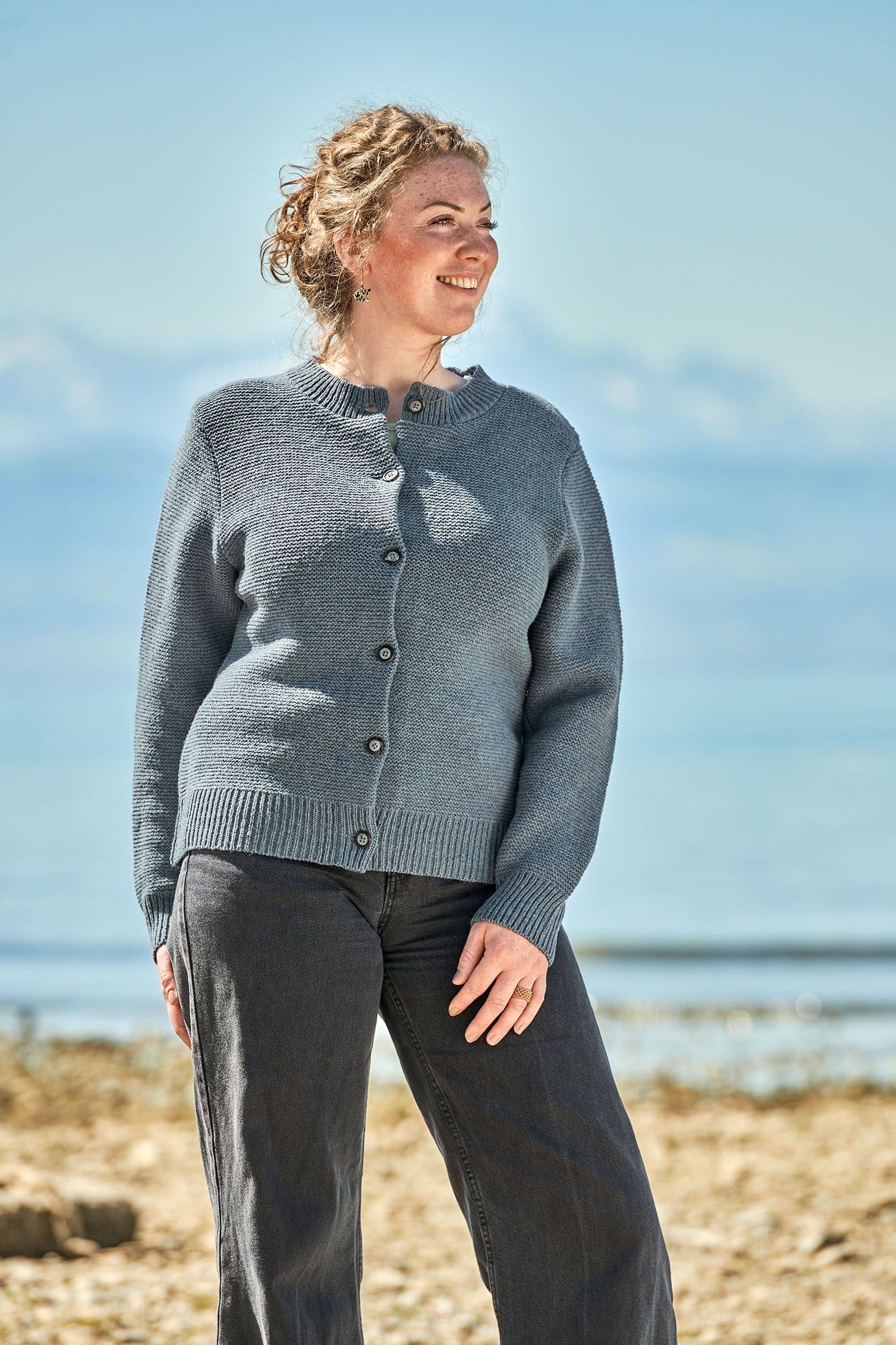 Finkhof-Damenstrickjacke rauchblau Gr. M Frau trägt eine schwarze Jeans und eine rauchblaue Strickjacke vom Finkhof aus bio Merinowolle (kbT)