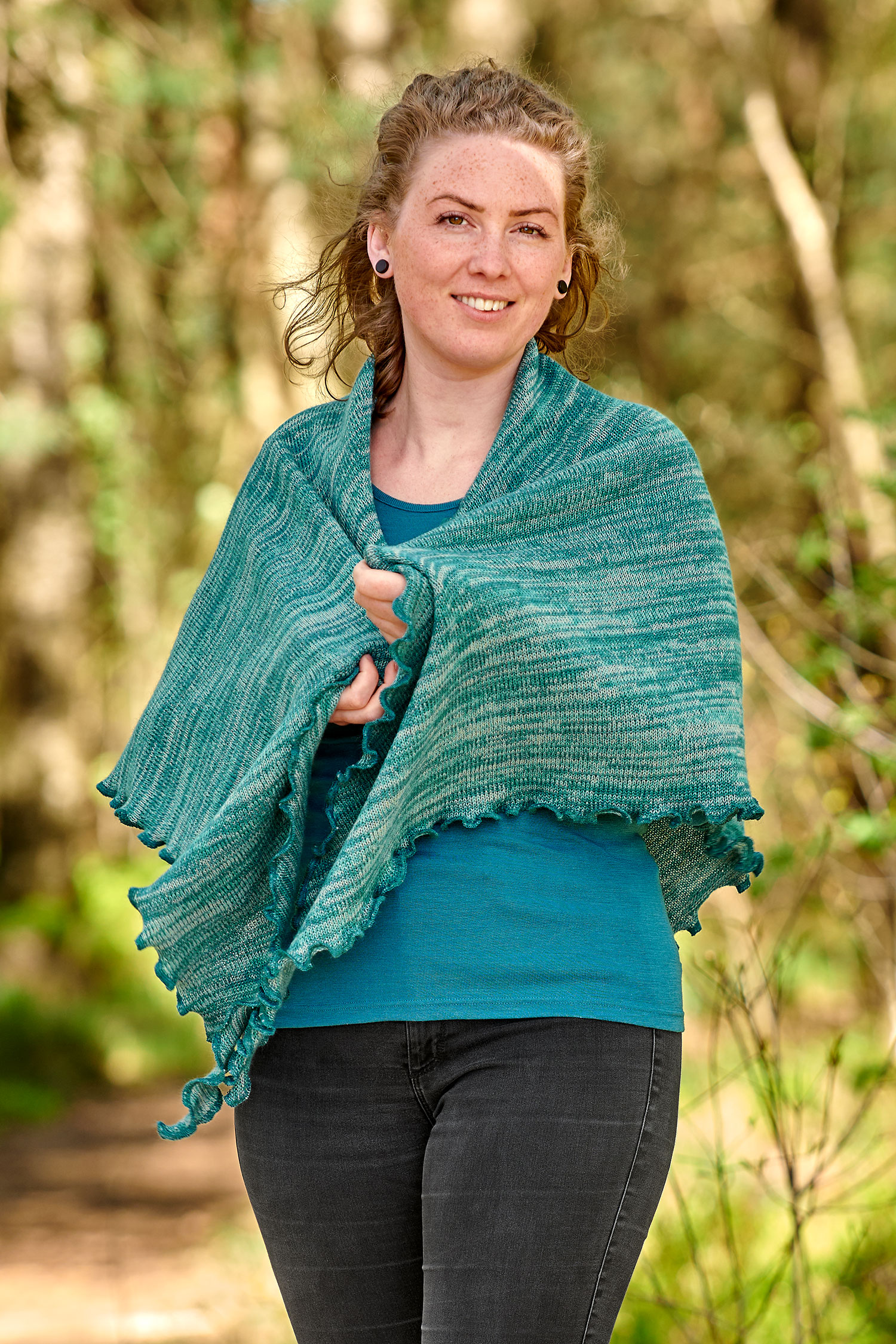 Frau mit türkisem Shirt trägt ein türkismeliertes Dreieckstuch aus bio Baumwolle (kbA) und bio Merinowolle (kbT)