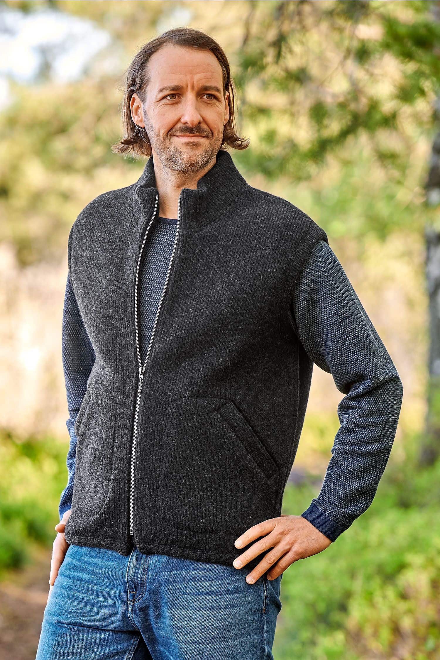 Finkhof-Wollwalkweste gefärbt anthrazit Gr. XL Mann mit grauem Pulli trägt anthrazitfarbene Wollwalkweste aus bio Wolle (kbT) ohne Ärmel vom Finkhof