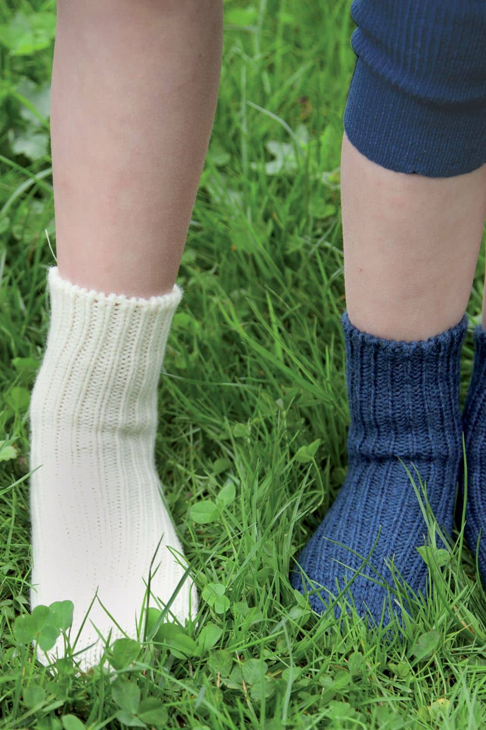 Wollsocken für Kinder Kinder im Gras tragen naturweiße und blaue Wollsocken