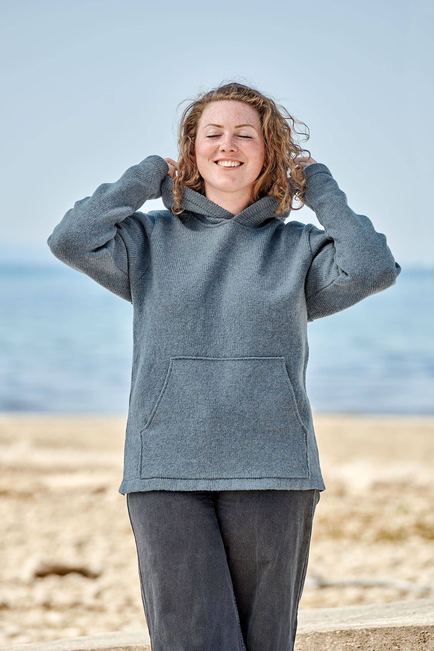 Frau trägt rauchblauen Kapuzenpullover aus bio Merinowolle (kbT) vom Finkhof