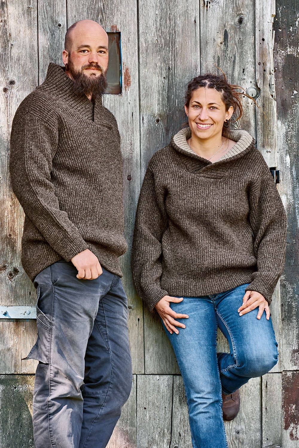 Finkhof-Schalkragenpullover braun Frau und Mann vor Holzwand tragen braune Schalkragenpullover