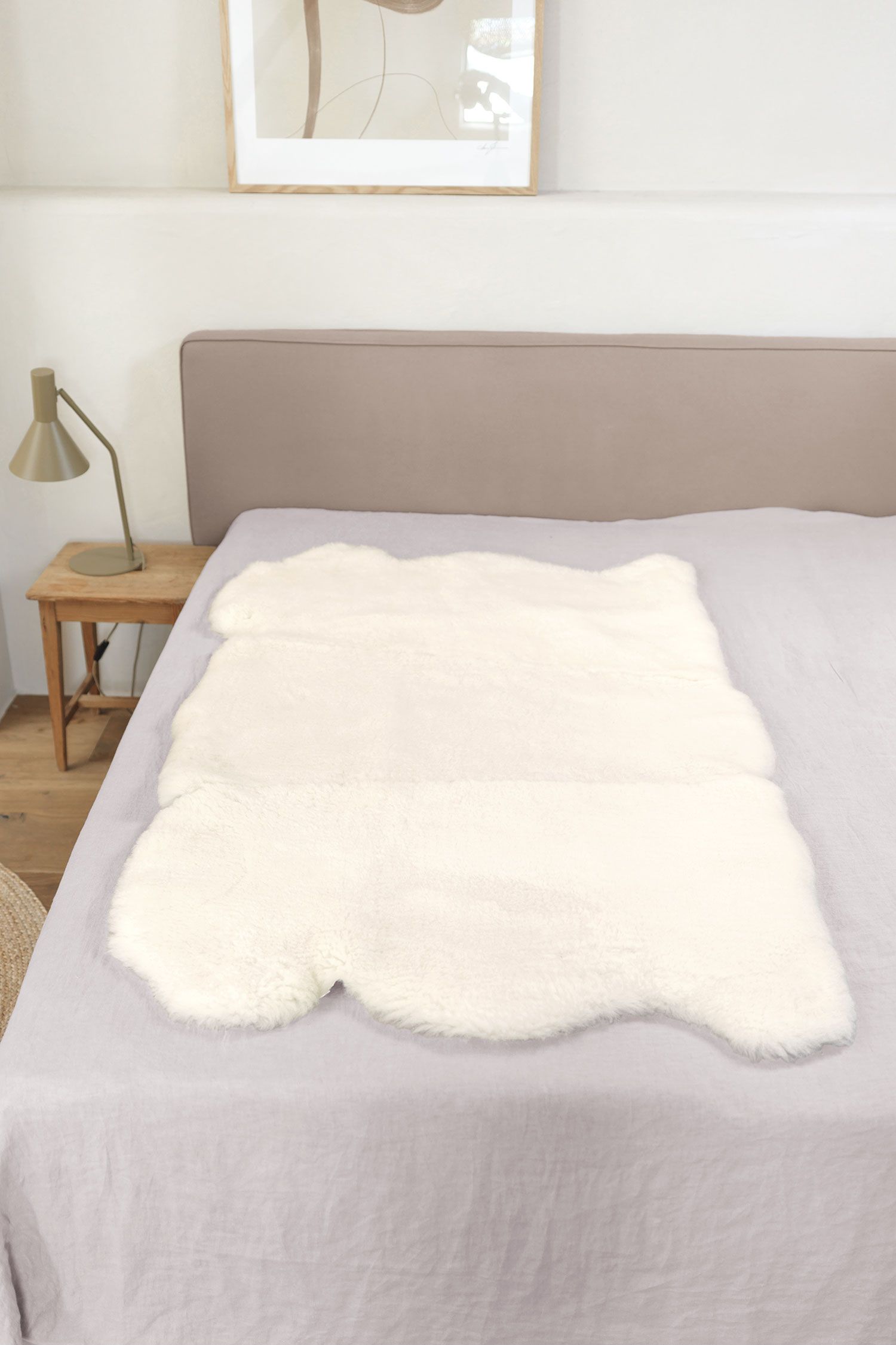 Felldecke natürliche Fellform pflanzlich, weiß 90 x 150 cm weiße pflanzlich gegerbte Felldecke in natürlicher Form aus Schaffell vom Finkhof auf grauem Bett