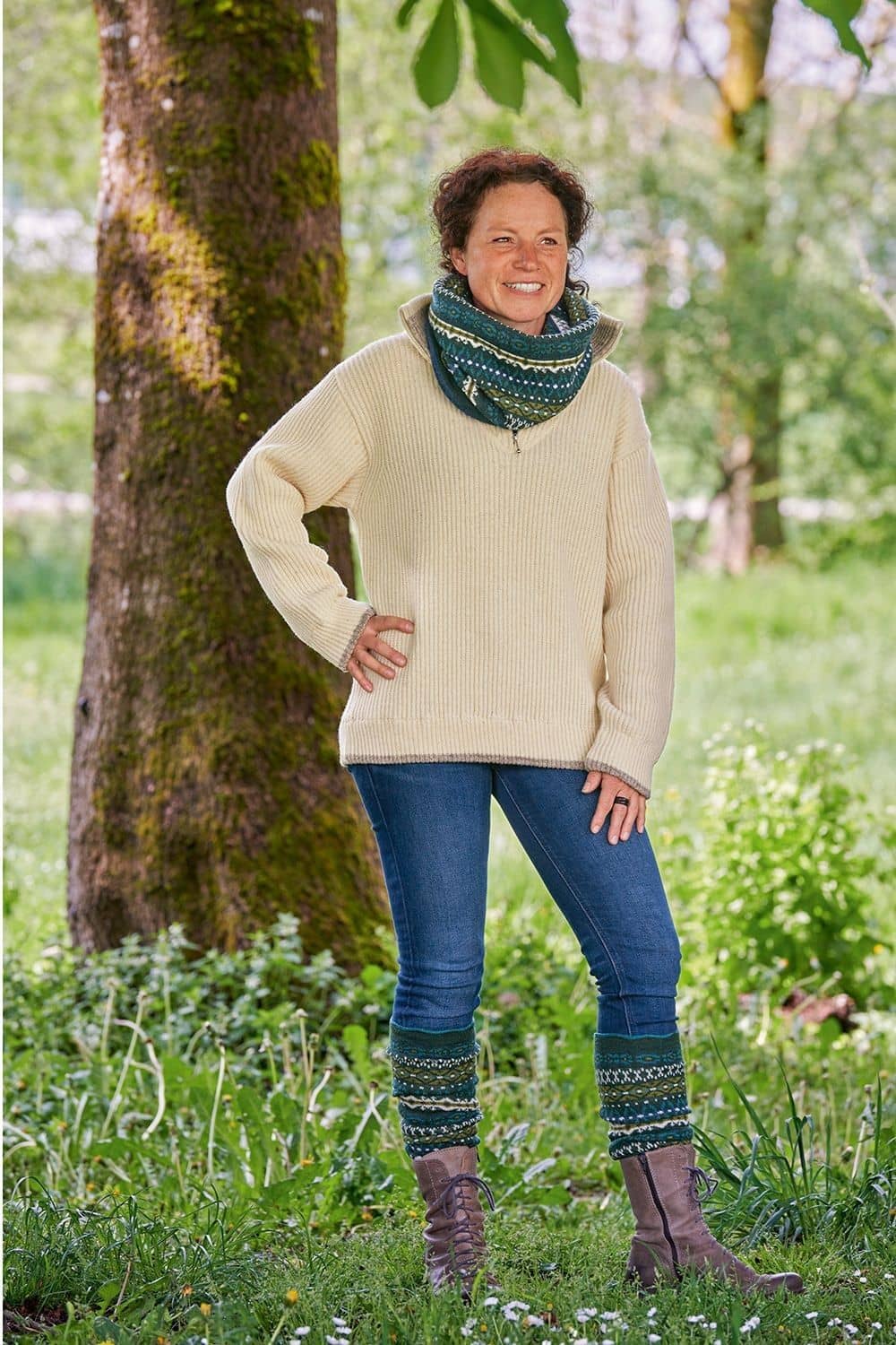 Frau mit gemusterten Stulpen und Schal trägt naturweißen Finkhof Troyer aus bio Wolle (kbT) mit Zipper