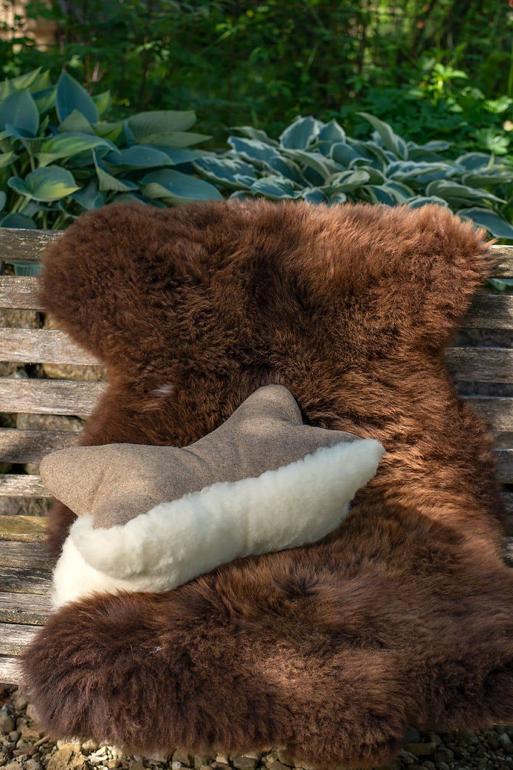 auf Holzbank liegt braunes Fell und Finkhof Leseknochen aus pflanzlich gegerbtem Schaffell, Loden und Rohwolle (kbT)