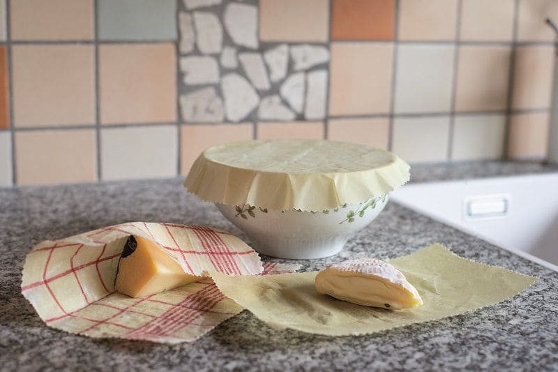 Schüsseln und Käse mit Bienenwachstücher auf grau melierter Arbeitsfläche