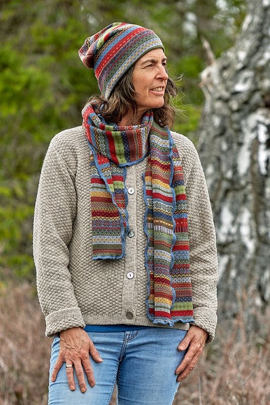 Mütze Oslo bunt gemusterte Mütze Oslo mit passendem Schal von Frau mit grauer Strickweste getragen