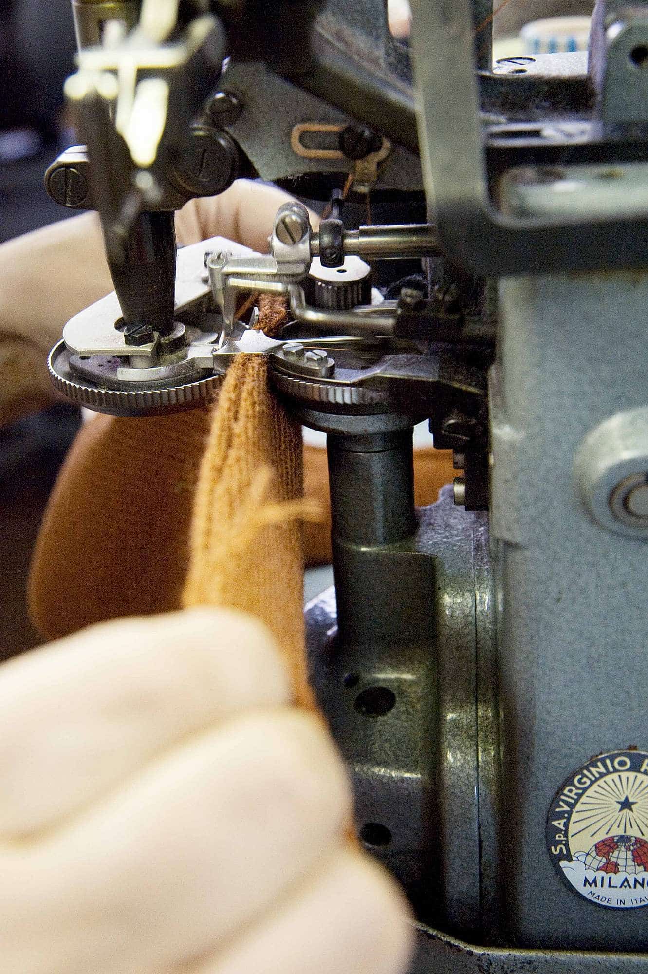 ueber-uns-unsere-wolle-strickerei-web-168 oranger Stoff wird in Finkhof Nähmaschine von Hand verarbeitet