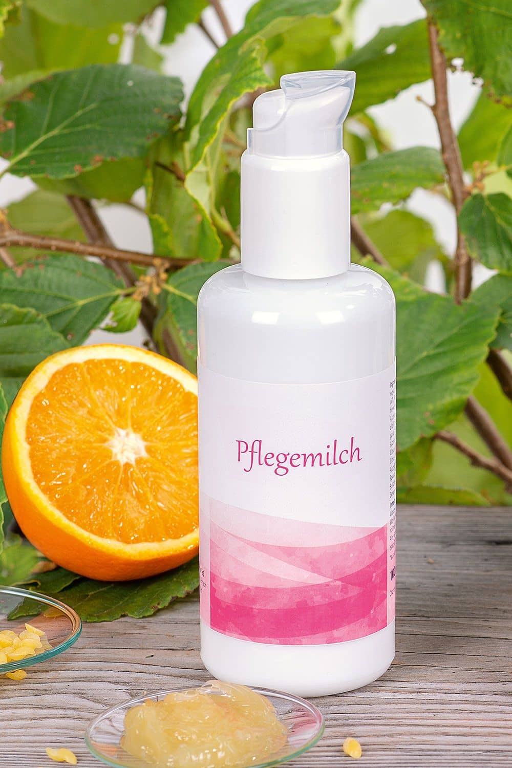 Naturkosmetik in Glas-Pumpspender: Pflegemilch 150 ml vom Finkhof mit Wollwachs & Olivenöl, Bild mit Orange und Blättern