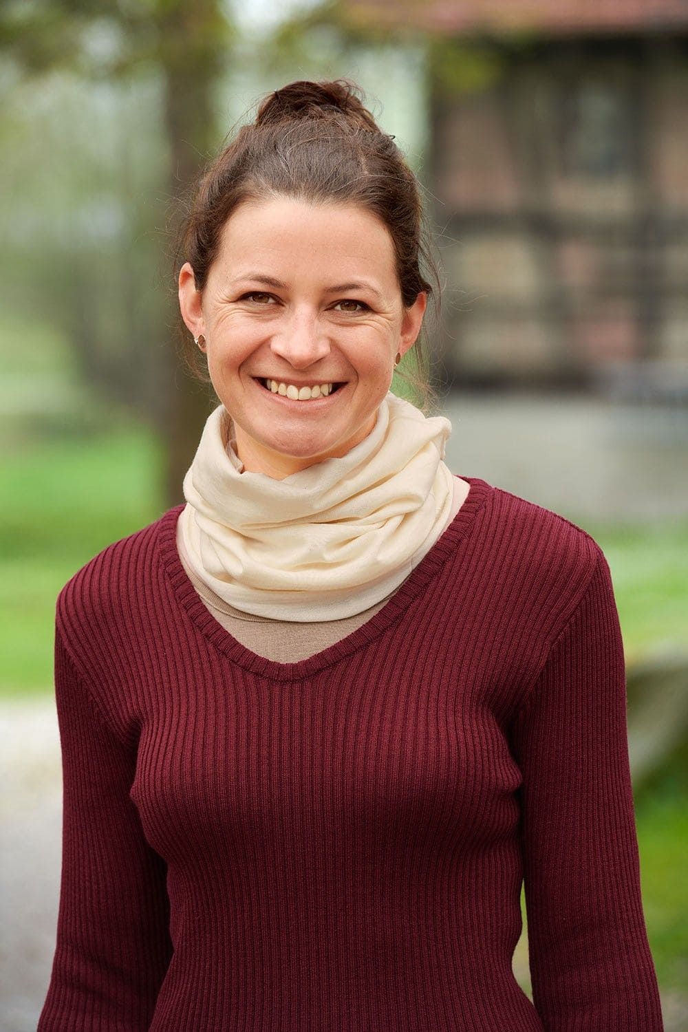 Frau mit rotem Rippshirt trägt naturweißen Sportschal aus bio Wolle (kbT) und Seide