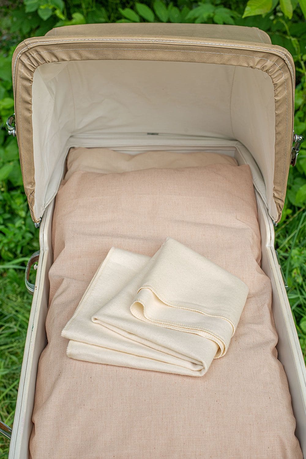 beiges Moltontuch aus bio Baumwolle (kbA) in altem Kinderwagen mit Korbschale, Verdeck und hellem Kissen