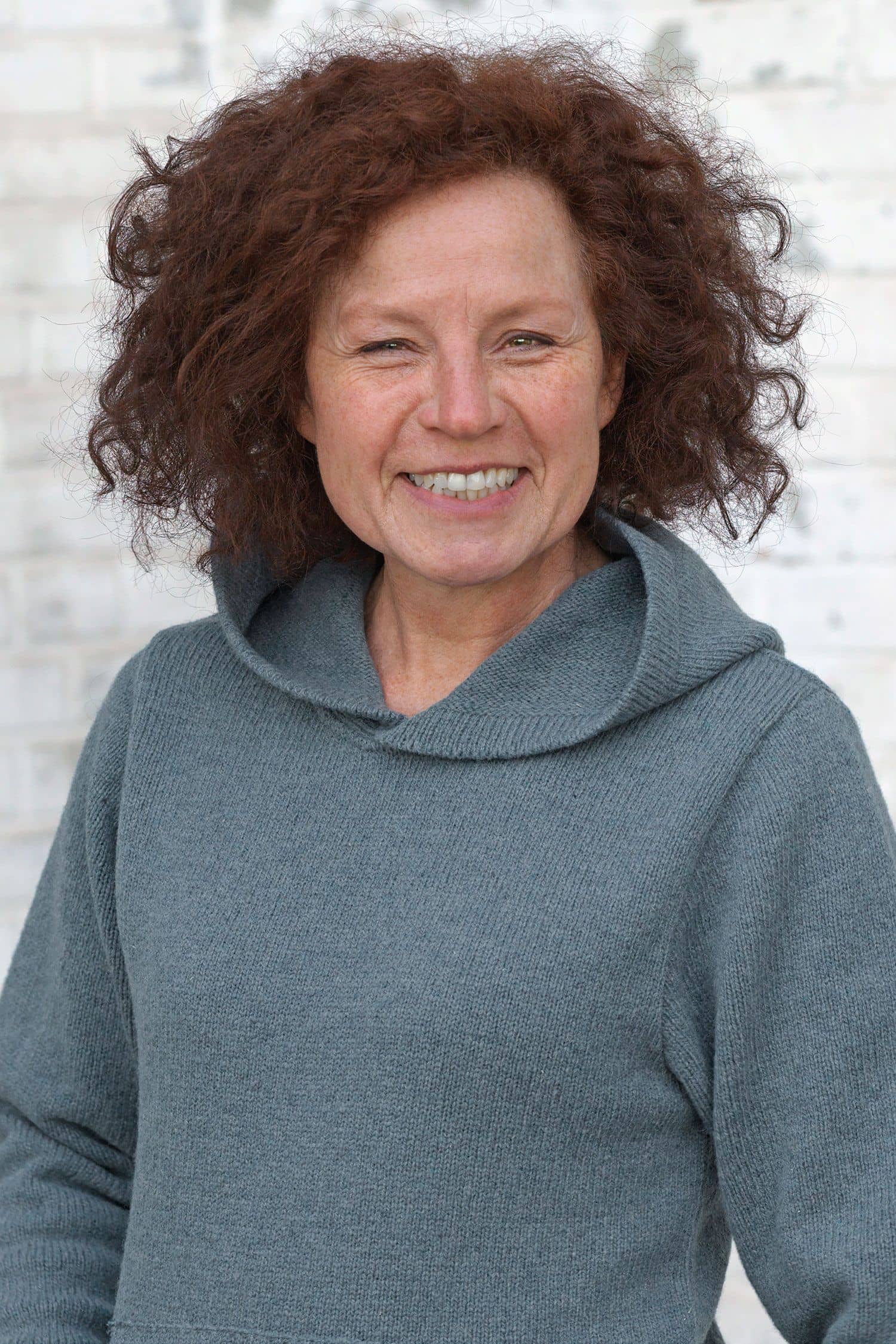 Frau trägt rauchblauen Kapuzenpulli aus bio Merinowolle (kbT) vom Finkhof