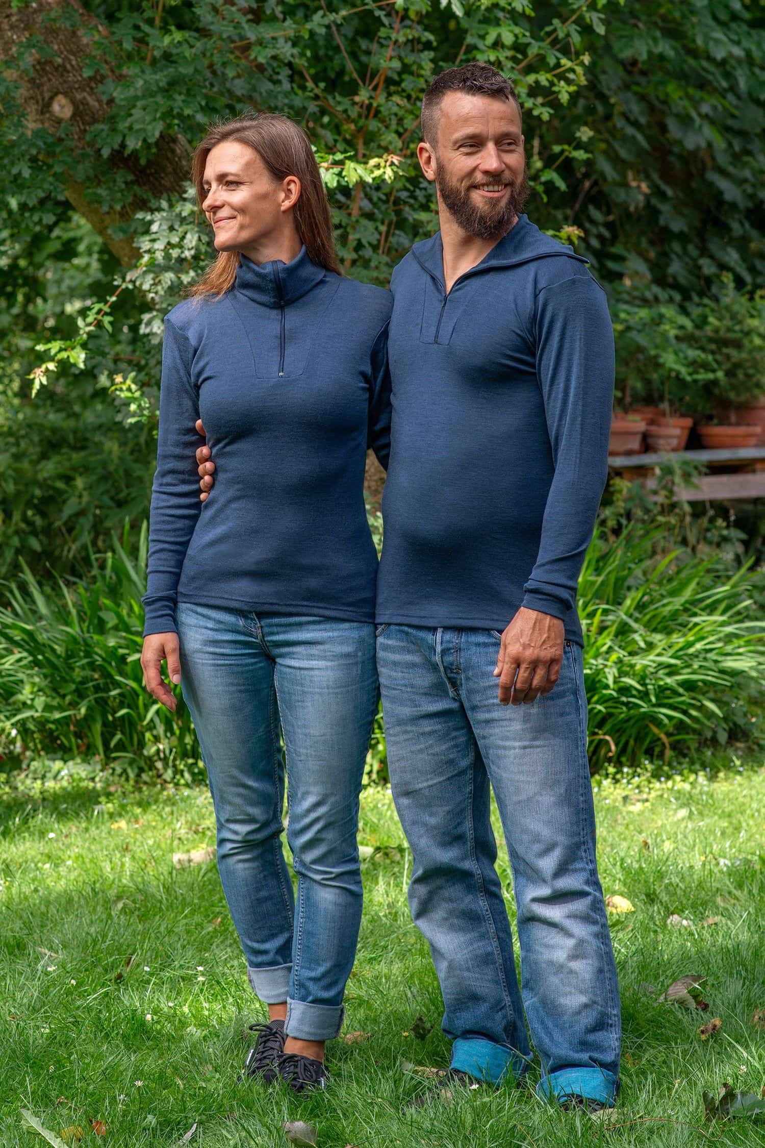 Mann und Frau im Garten tragen Jeans und marineblauen Sportrolli aus bio Wolle (kbT) und Seide mit Reißverschluss