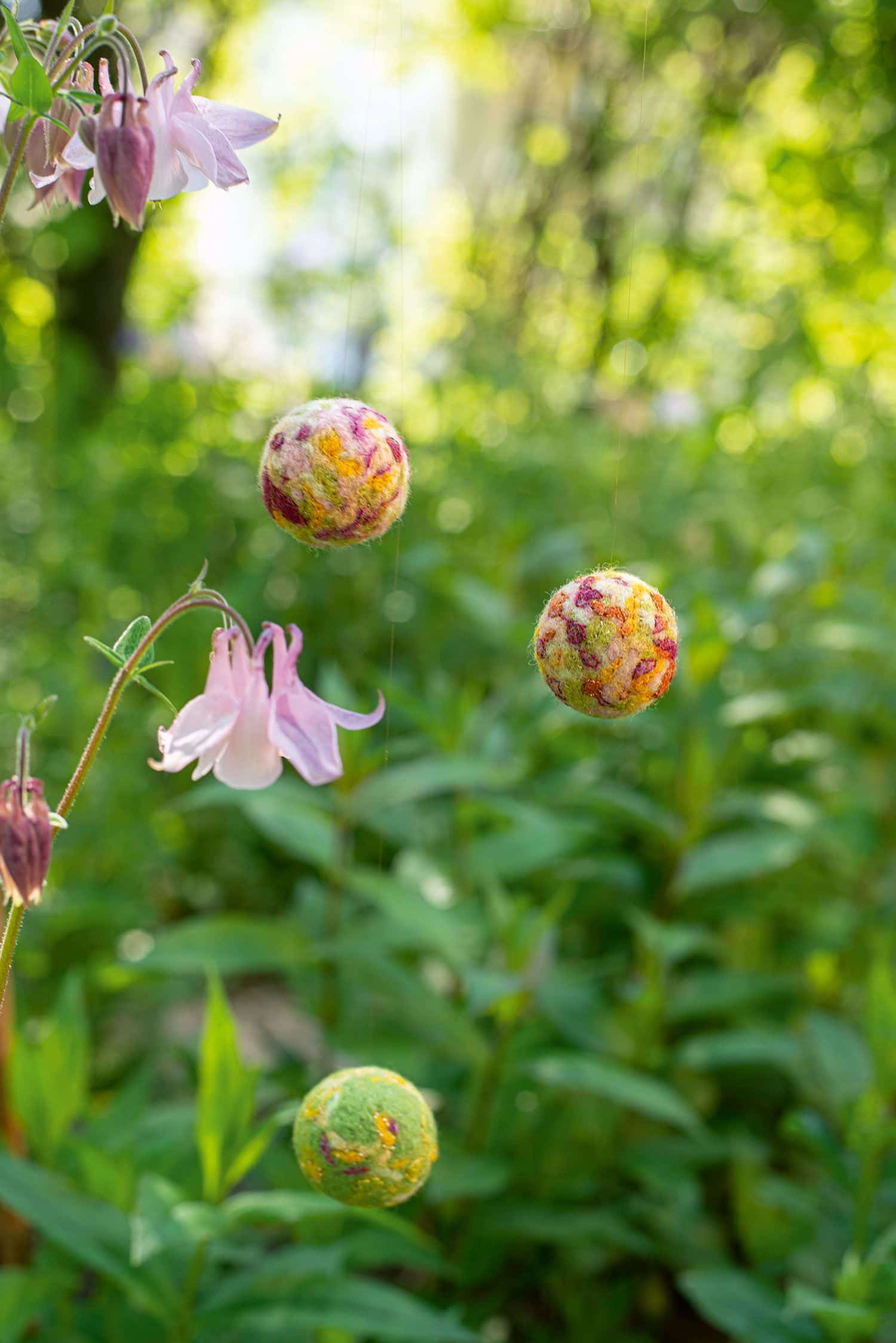aufgehängte Filzkugeln mit Wiese im Hintergrund