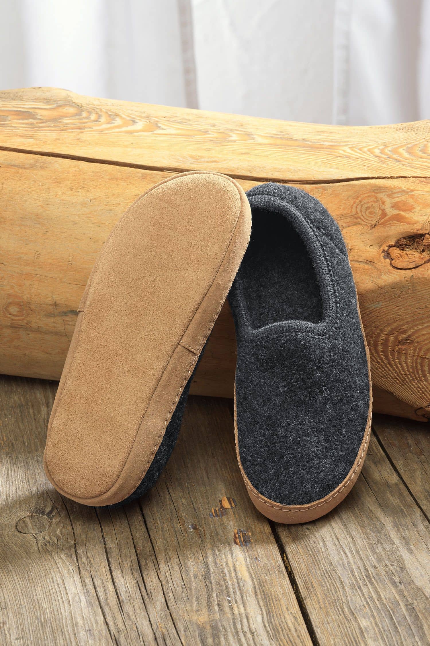 Paar graue Finkhof Hausschuhe aus bio Wolle (kbT) und Sohle aus pflanzlich gegerbtem Rindsleder auf Baumstamm von unten