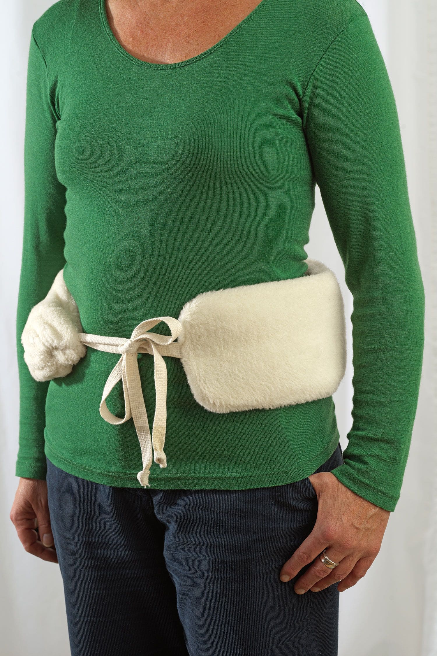 Frau hat sich lange Wärmflasche mit Lammflorbezug aus Wolle und bio Baumwolle (kbA) vom Finkhof um Bauch geschnallt