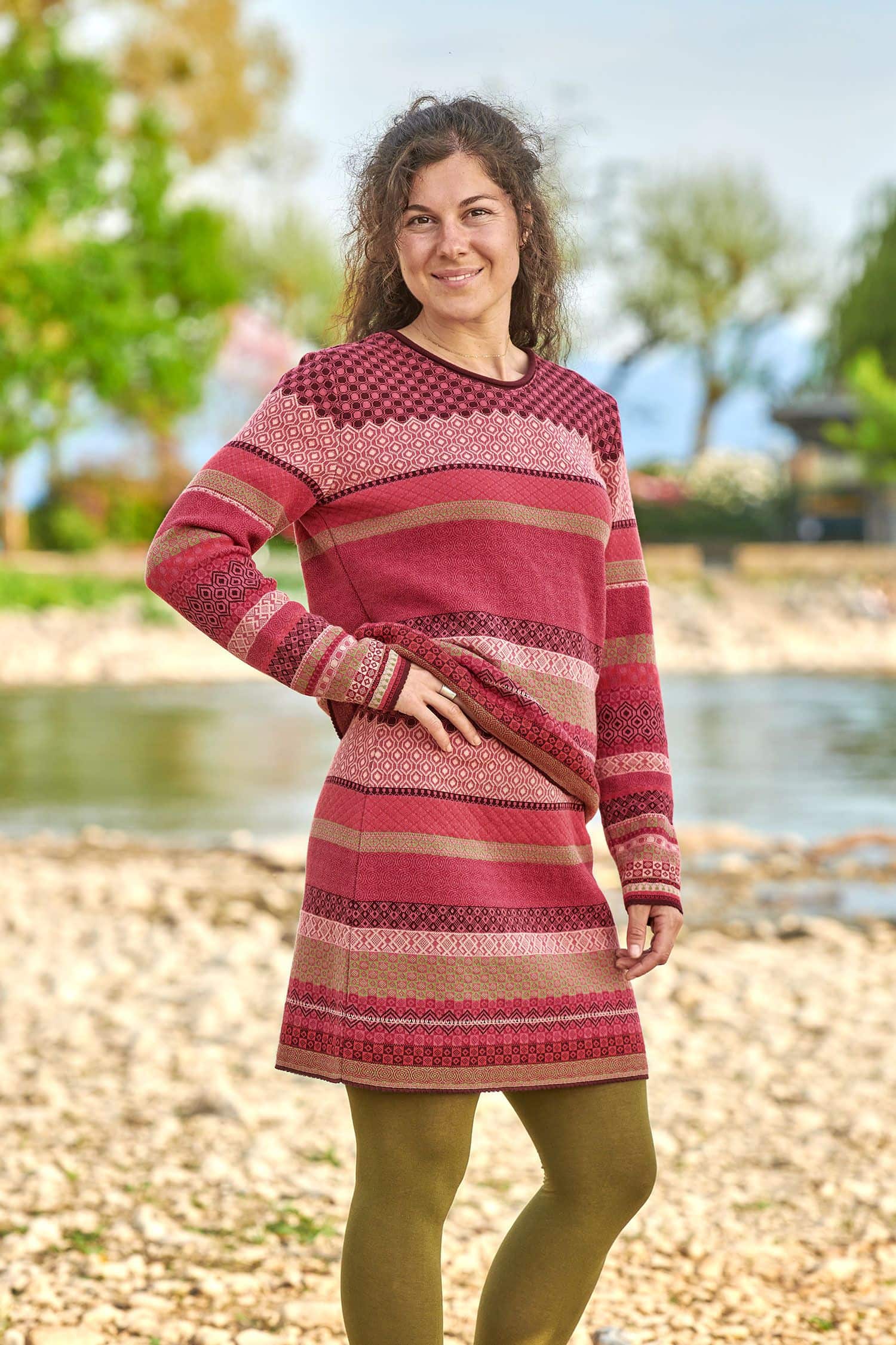 Frau trägt gemusterten Rock und Pulli in beere und pink aus bio Baumwolle (kbA) mit grüner Strumpfhose