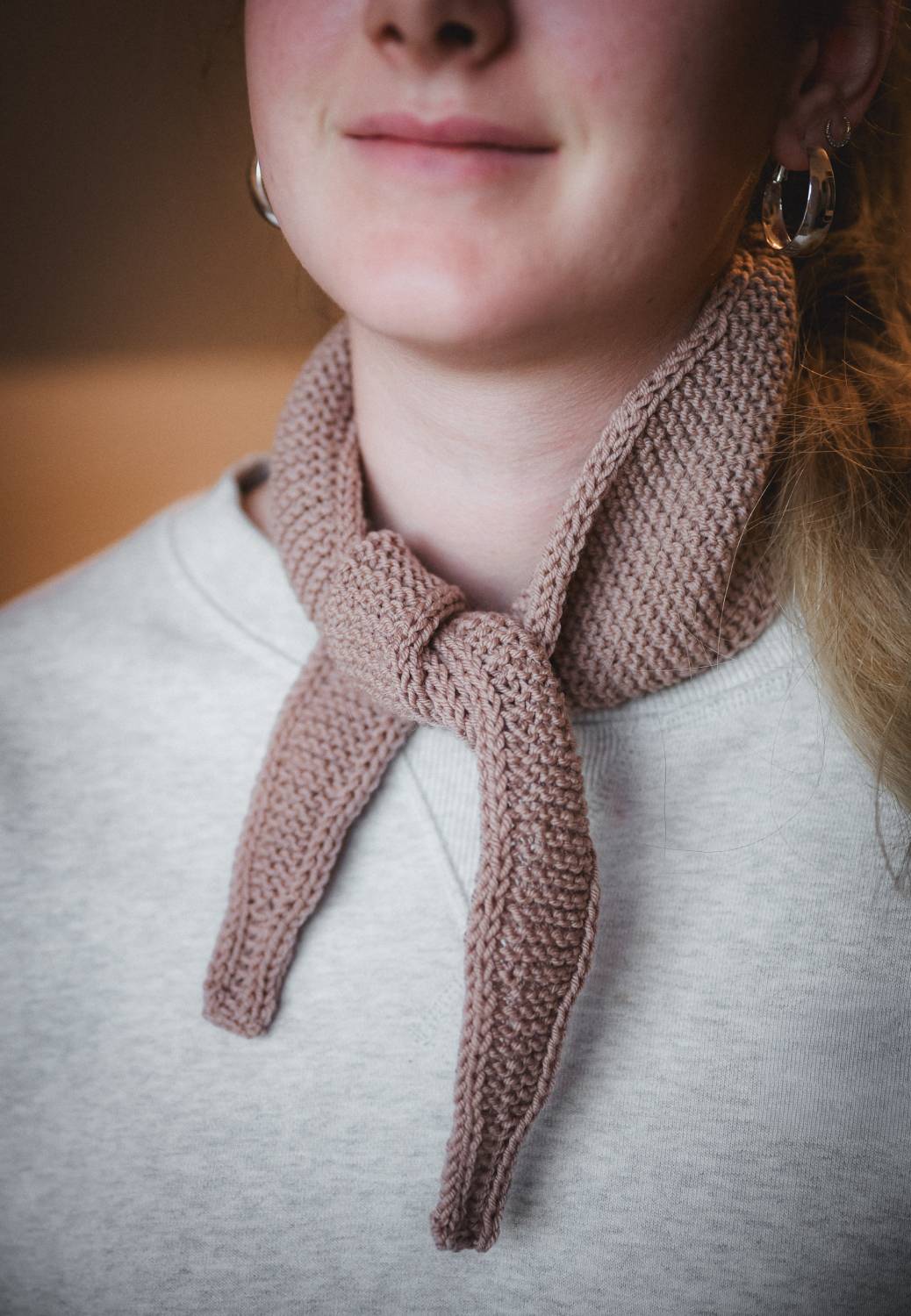 Frau trägt grauen Pullover und rosafarbenen Schal aus einer Wolle vom Finkhof