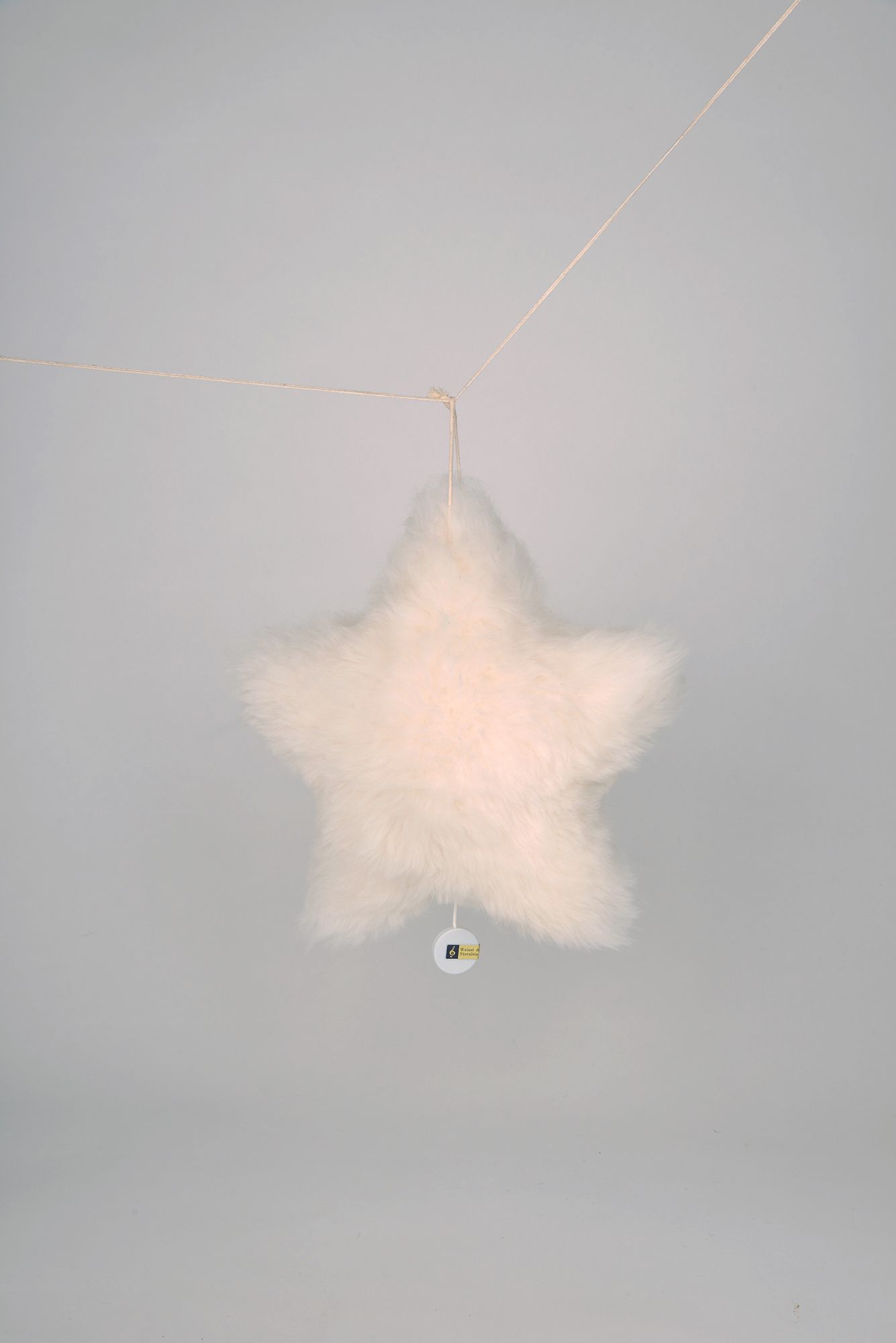 weiße Sternenspieluhr vom Finkhof aus bio Wolle (kbT) und Fell hängt auf Schnur