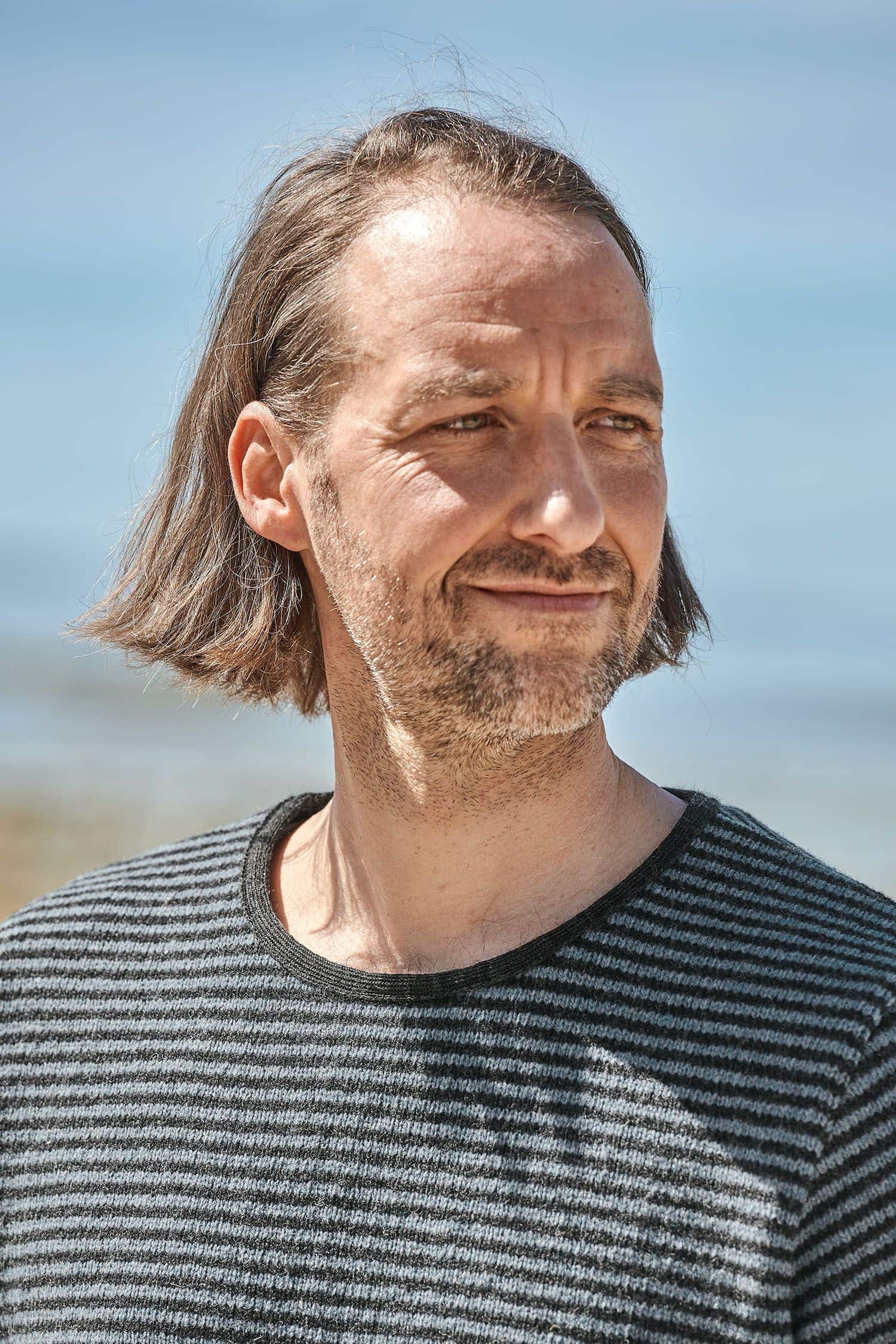 Mann trägt einen rauchblauen Ringelpulli vom Finkhof aus bio Merinowolle (kbT)