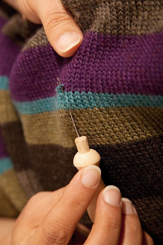 Einziehnadel Metall Einziehnadel mit Holzgriff in Verwendung bei bunt gestreiftem Strickstück