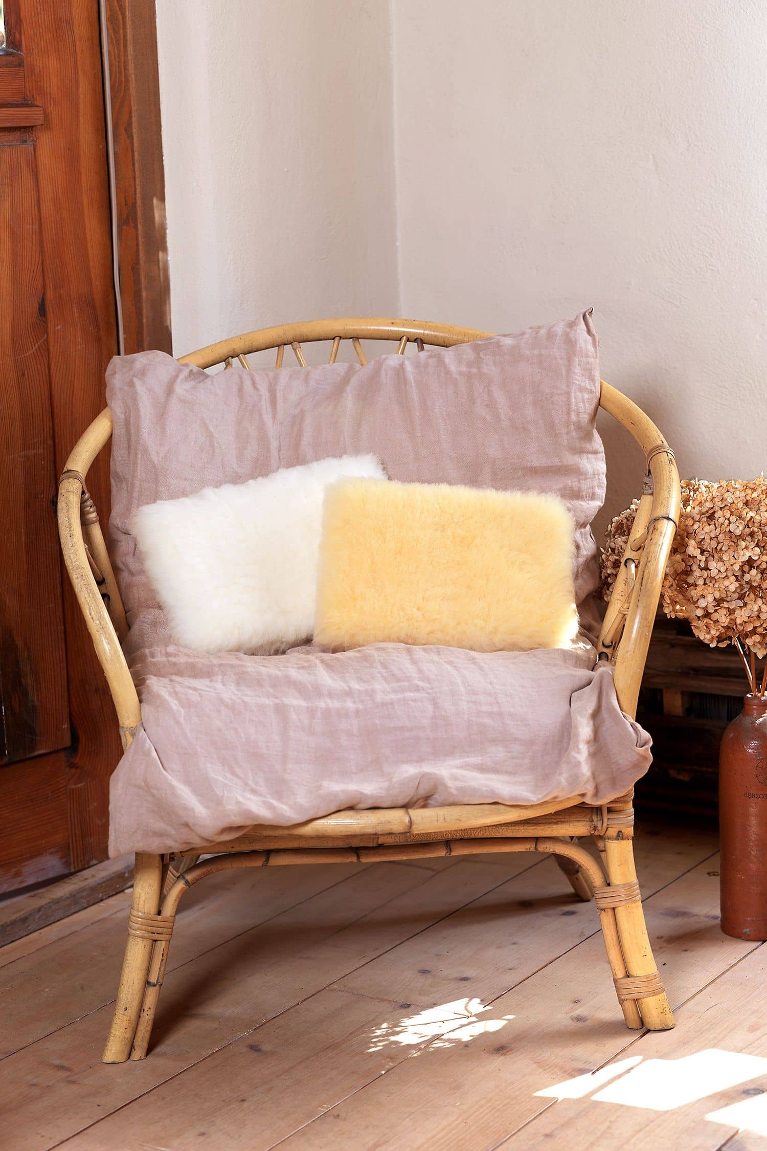 Kuschelkissen Korbstuhl mit altrosa Decke und Kuschelkissen aus Schaffell vom Finkhof