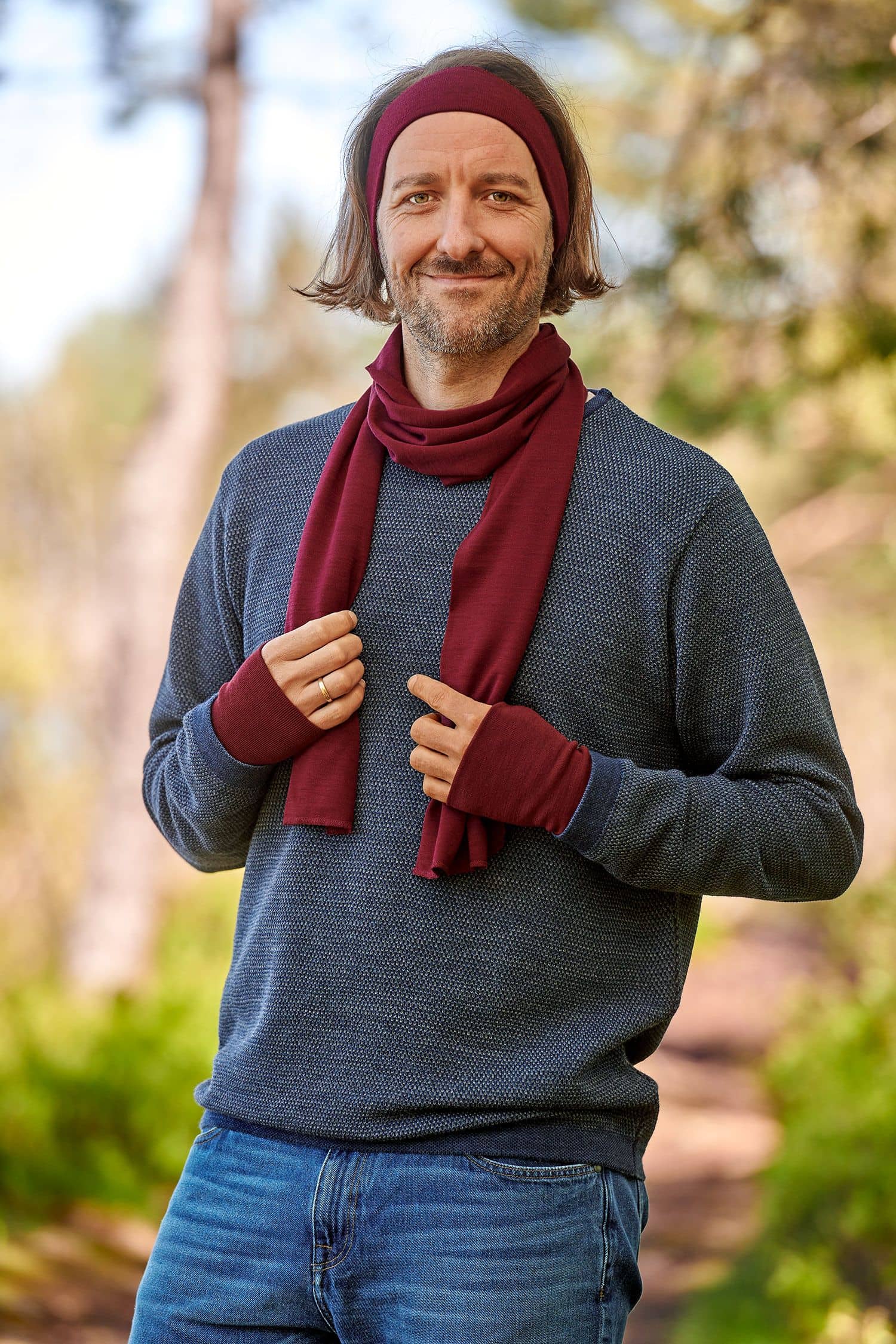 Mann mit grauem Pulli trägt einen bordeauxroten Schal aus bio Wolle (kbT) und Seide mit passendem Stirnband