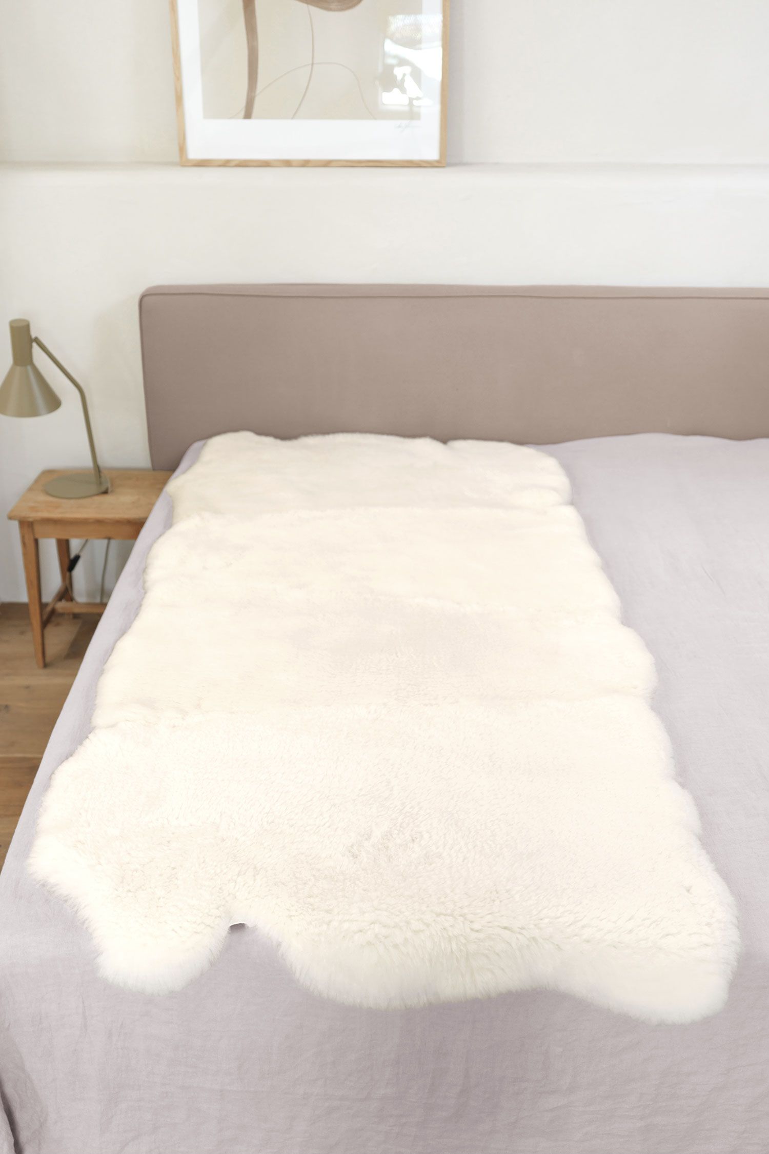Felldecke natürliche Fellform pflanzlich, weiß 90 x 200 cm weiße pflanzlich gegerbte Felldecke in natürlicher Form aus Schaffell vom Finkhof auf grauem Bett