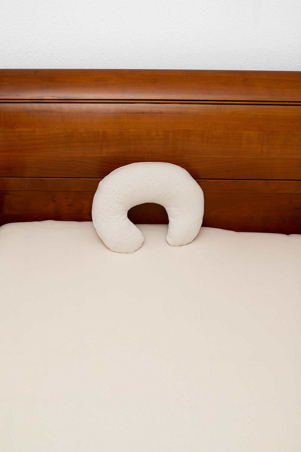 Nackenhörnchen Doppeljersey helles Finkhof Nackenhörnchen aus Doppeljersey mit bio Baumwolle (kbA) und bio Wolle (kbT) lehnt an dunkelbraunem Bett