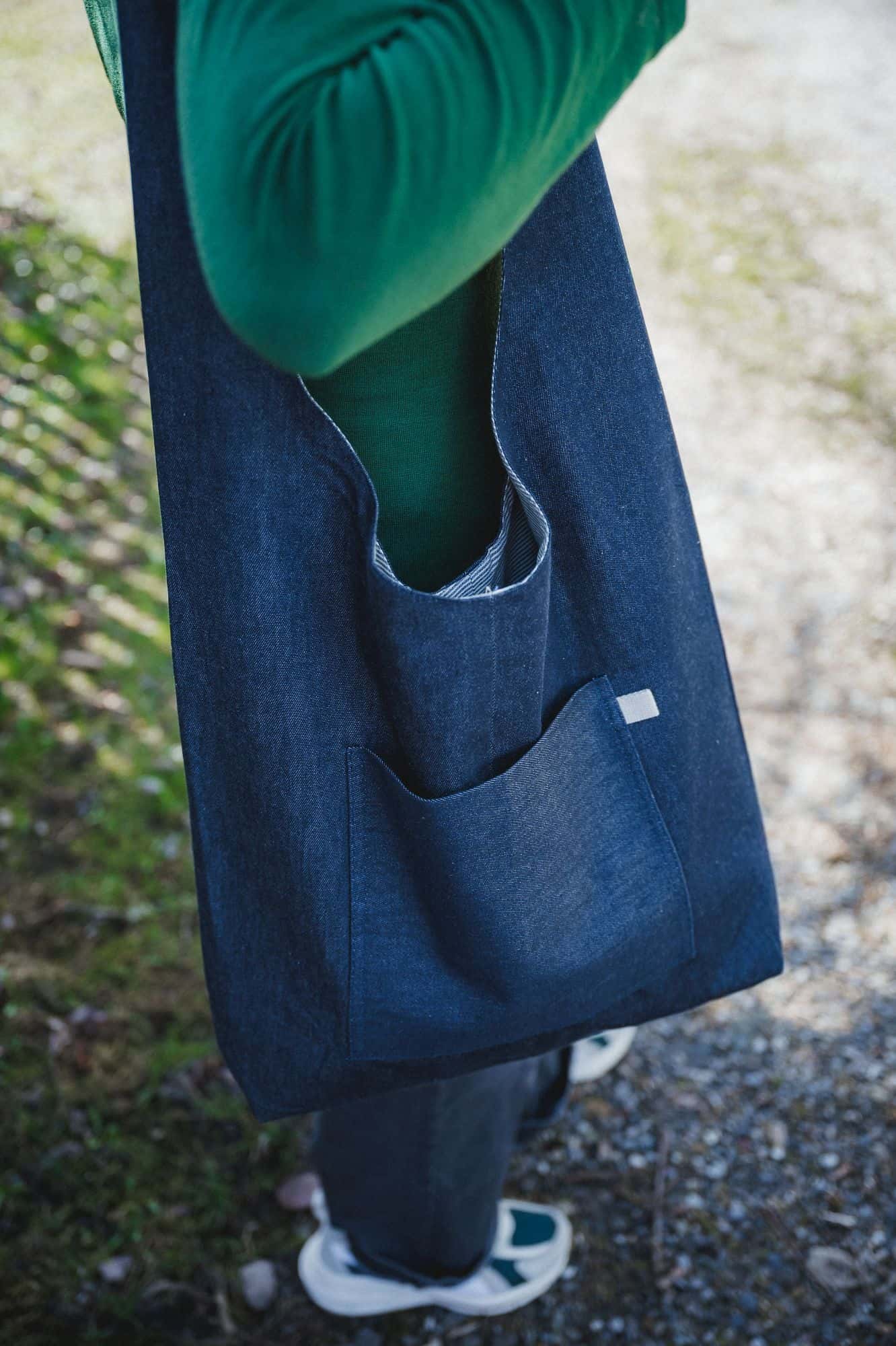 Frau mit grünem Langarmshirt trägt Shopper zum Wenden vom Finkhof aus Bio-Baumwolle über der Schulter