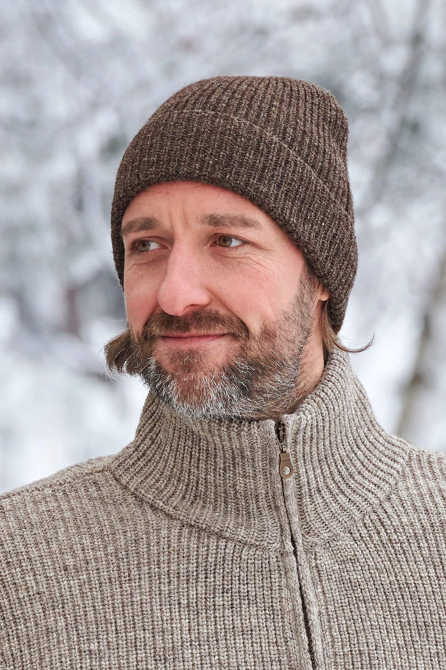 Mann trägt braunen Finkhof Troyer und eine dunkelbraune Finkhof Mütze aus bio Wolle (kbT)