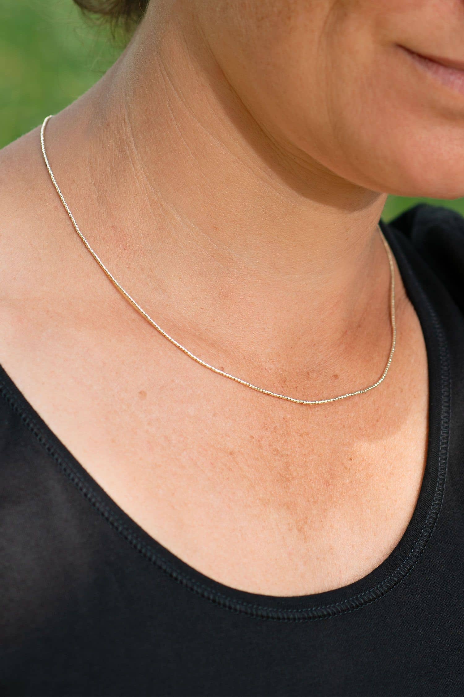 Feine Silberhalskette Karen Frau mit schwarzem Shirt trägt feine silberne Halskette