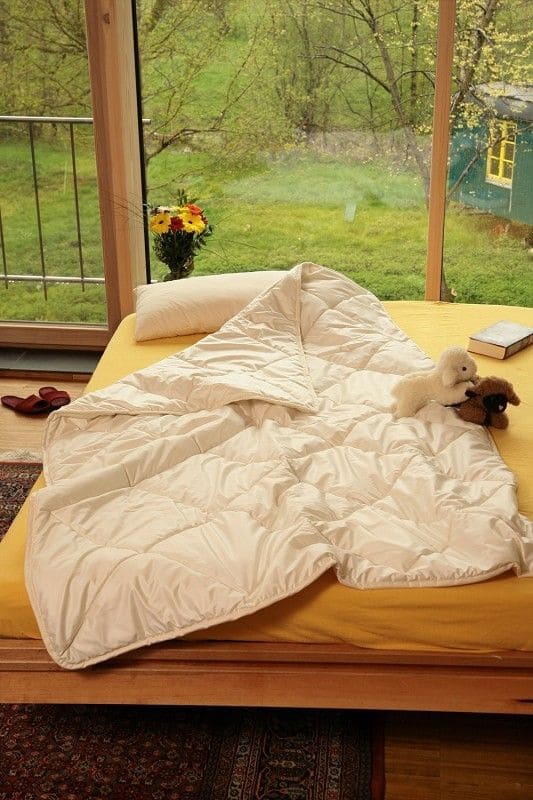 weiße Sommersteppdecke aus bio Wolle (kbT) und bio Baumwolle (kbA) vom Finkhof auf Bett mit gelbem Laken