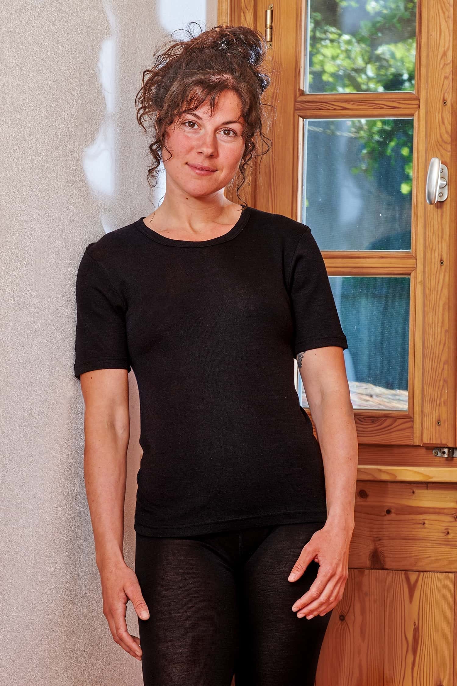 Frau trägt schwarzes Kurzarmshirt mit Rundhalsausschnitt aus Bio-Wolle und Seide