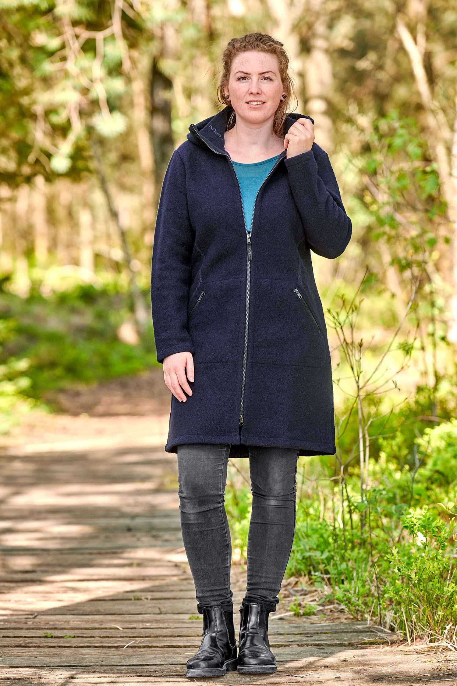 Frau mit türkisem Shirt und schwarzer Jeans trägt einen marineblauen Wollmantel