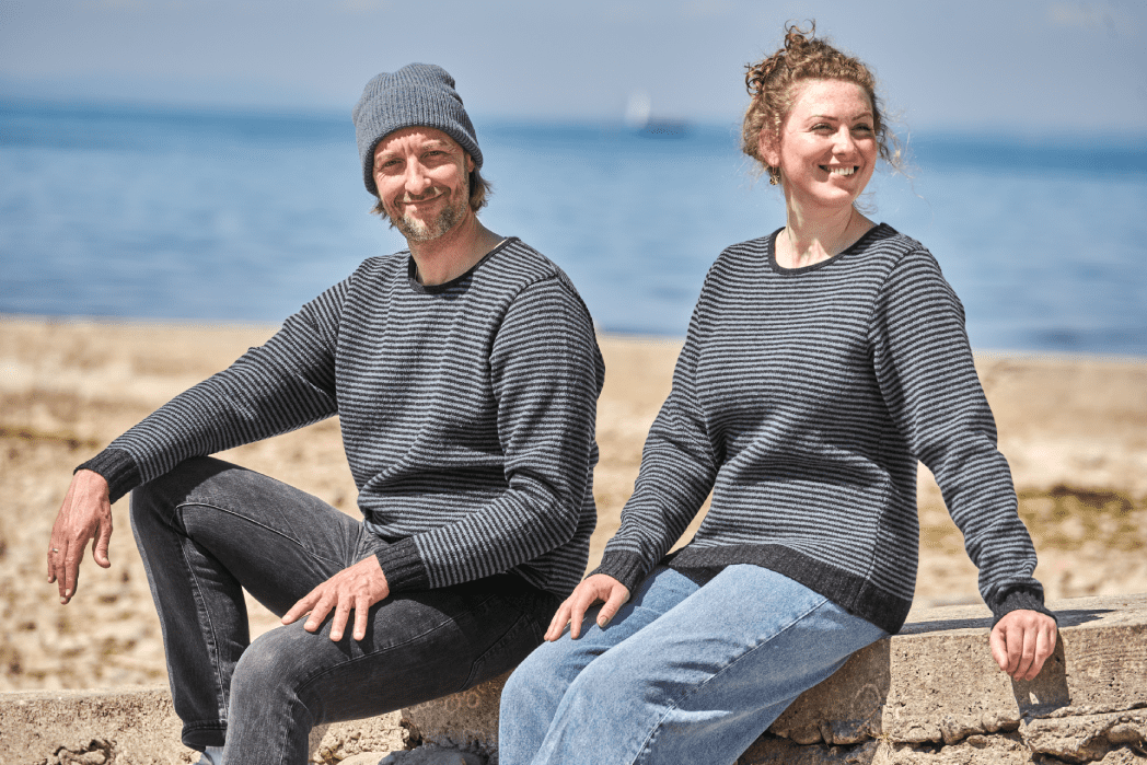 Was jetzt wärmt Mann und Frau sitzen mit Finkhof Streifenpullis auf einem Stein