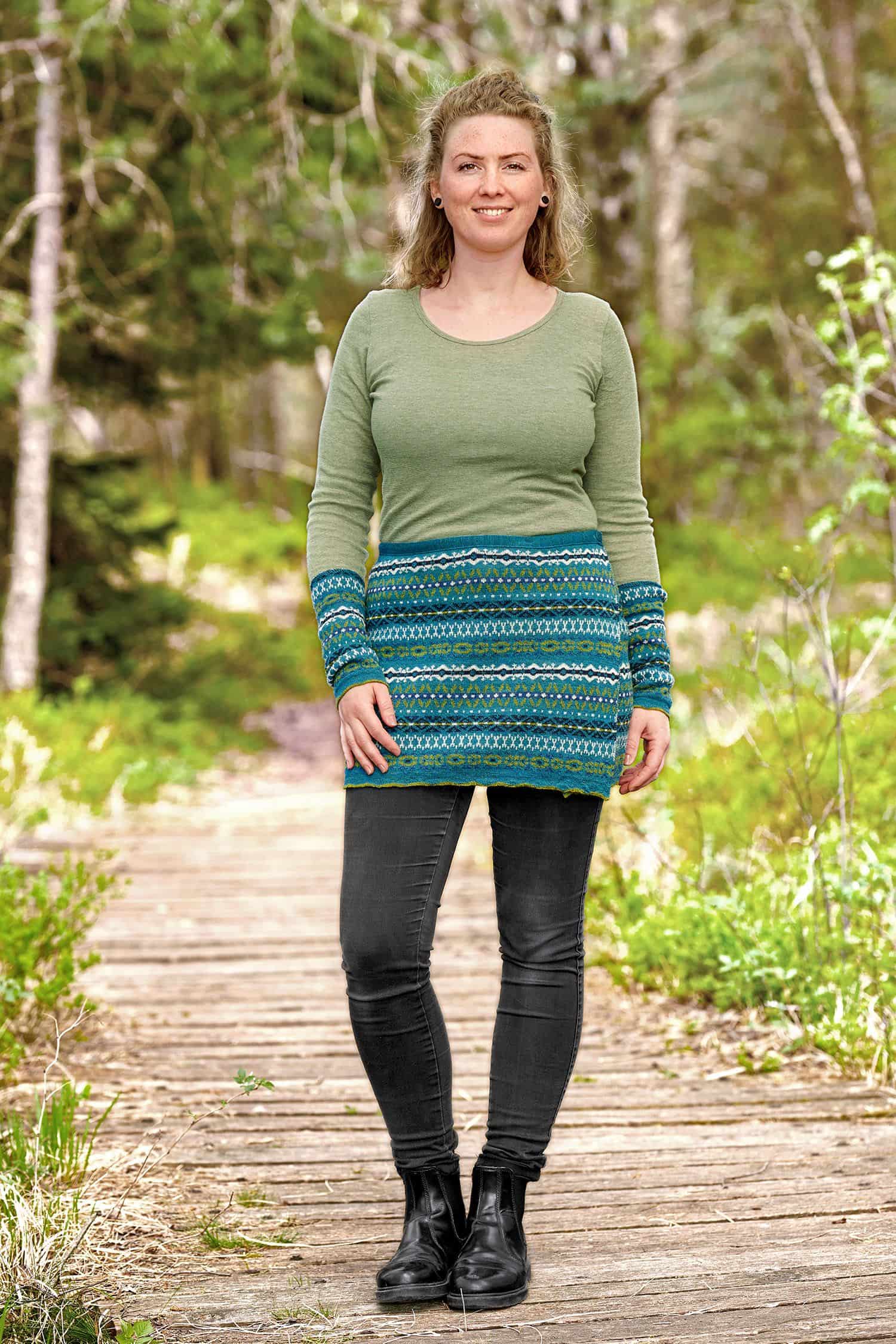 Cacheur Nordic Frau trägt einen türkisen Cacheur mit nordischem Muster aus bio Wolle (kbT) und ein grünes Shirt