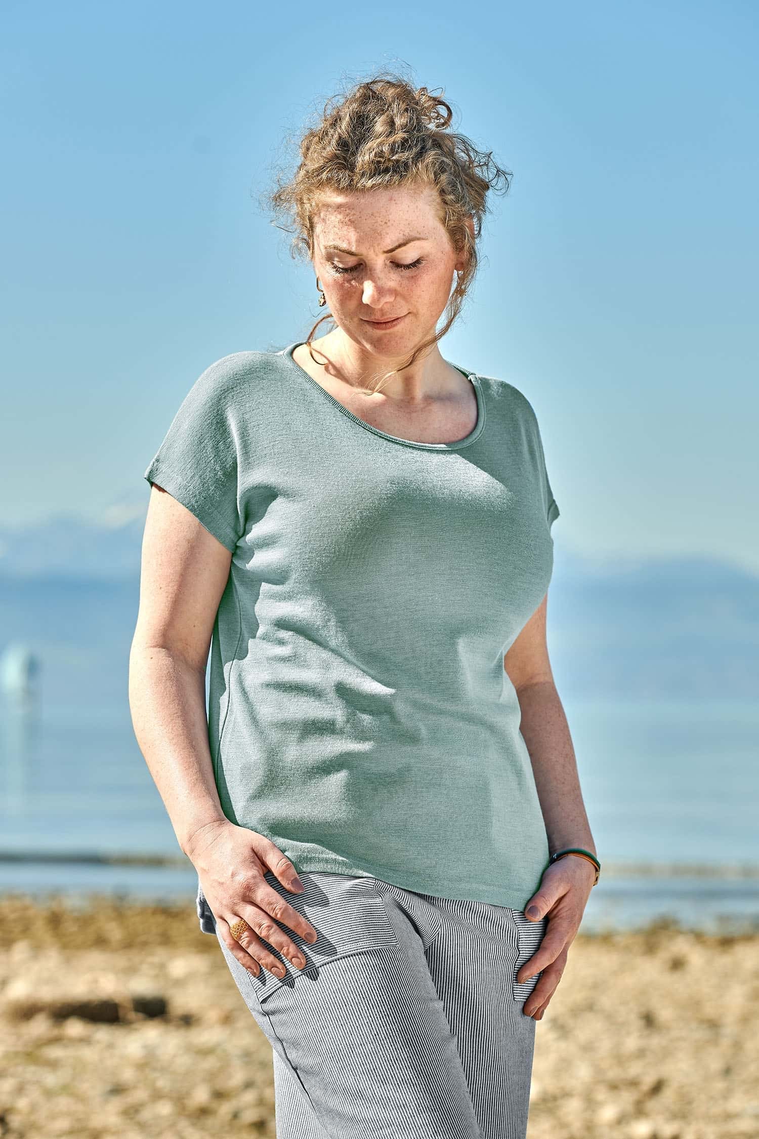 Damen-Oversize Shirt aus Wolle-Seide mit Bio-Fasern Frau mit blau weiß gestreifter Hose trägt ein pastellblaues Oversize Shirt aus Bio-Wolle und Seide mit GOTS