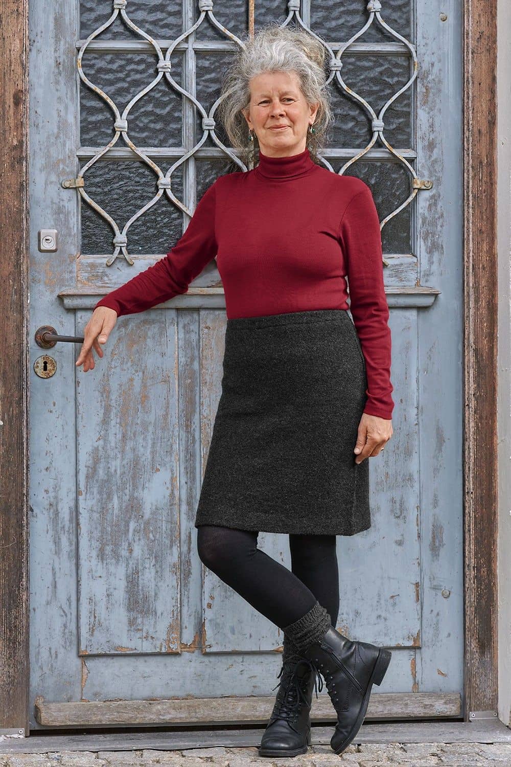 Frau trägt Rock, rotes Shirt, Strumphfhose, Stiefel und anthrazitgraue Struktursocken aus bio Wolle (kbT) vom Finkhof