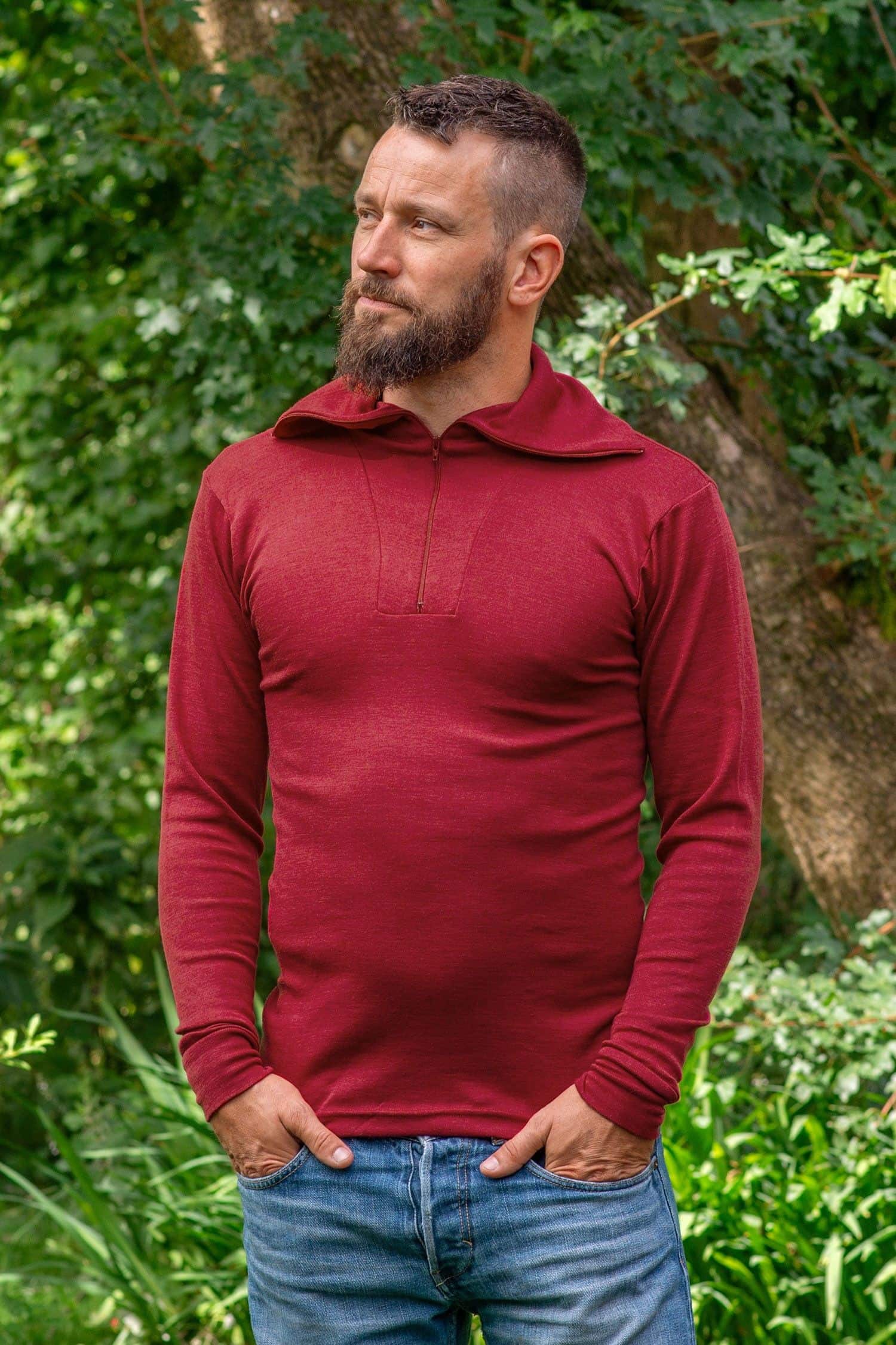 Mann steht im Garten und trägt Jeans und roten Sportrolli aus bio Wolle (kbT) und Seide mit Reißverschluss