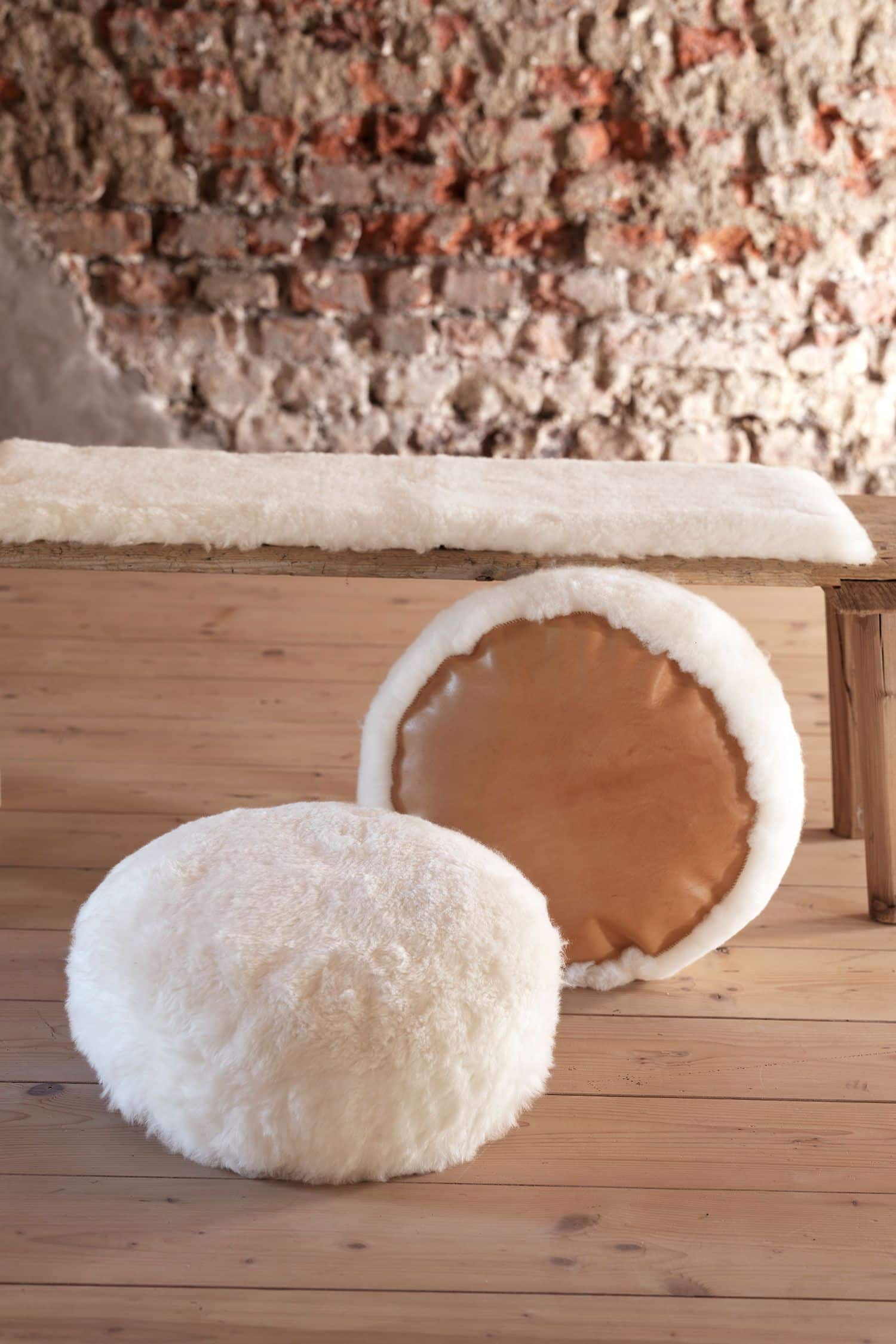 Bodenkissen aus pflanzlich gegerbten Fellen 38 cm weiße Finkhof Bodenkissen aus Schaffell, Ziegenleder und Wolle vor Bank mit Fellauflage