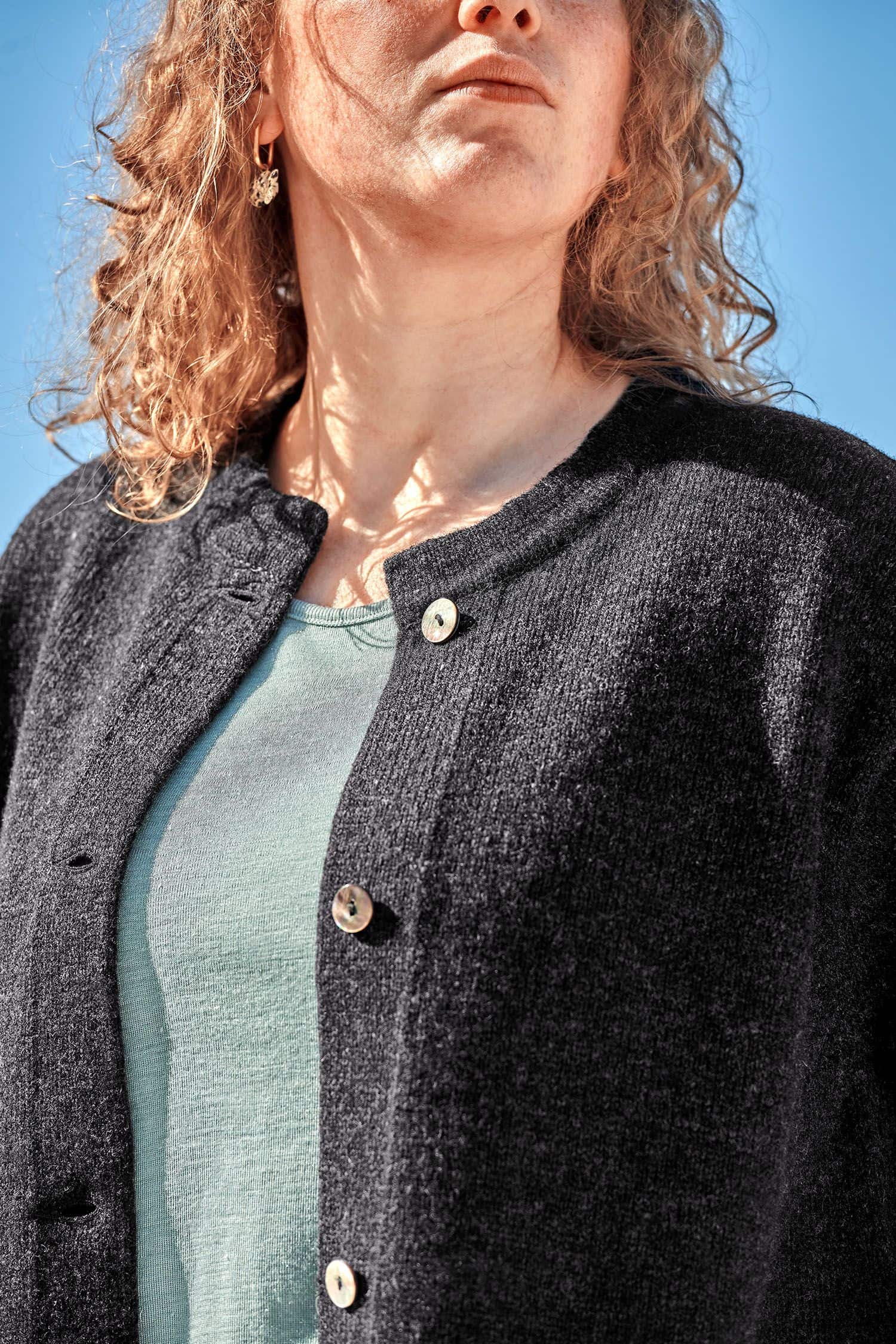 Frau trägt anthrazitgrauen Strickmantel aus bio Wolle (kbt) vom Finkhof und ein blaues Shirt