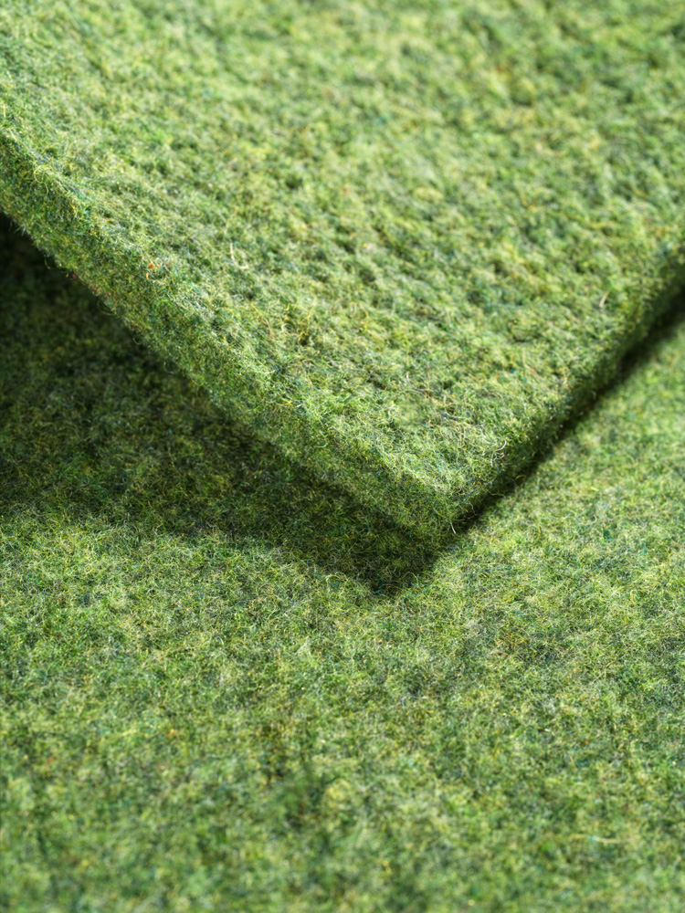 Nahaufnahme von grüner Finkhof Sitzauflage aus bio Wolle (kbT)