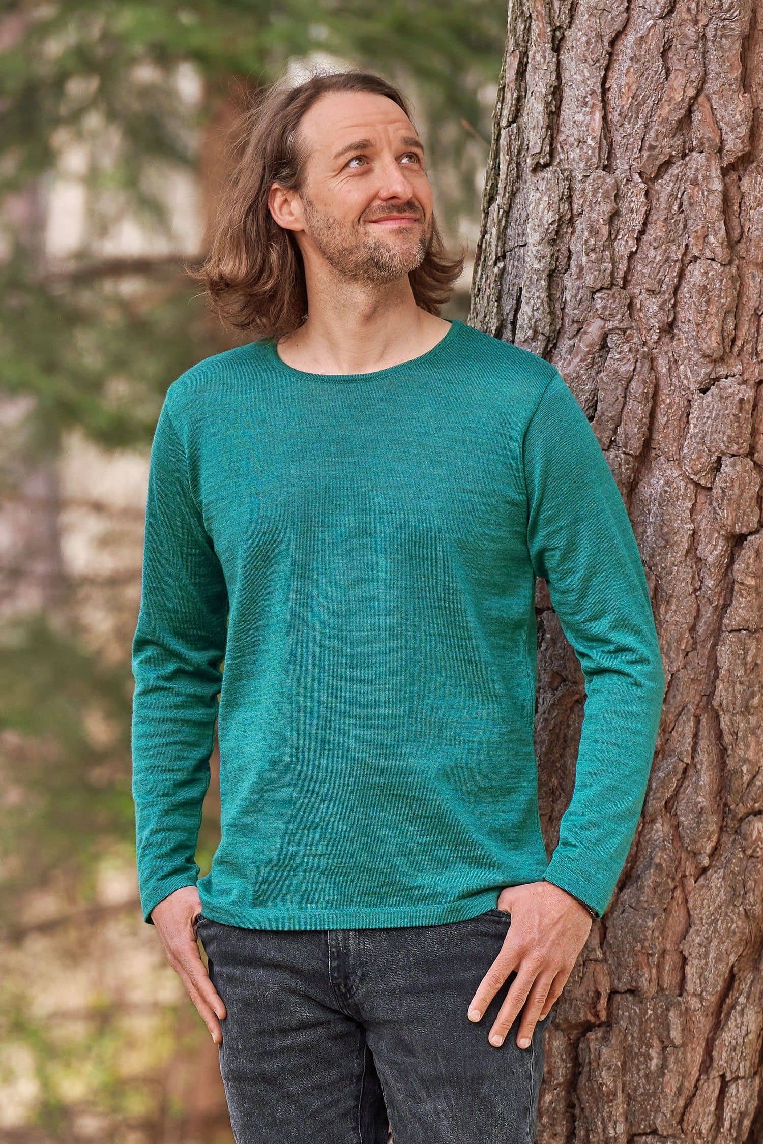 Mann steht vor Baum und trägt petrolblaues Wollshirt aus bio Wolle (kbT)