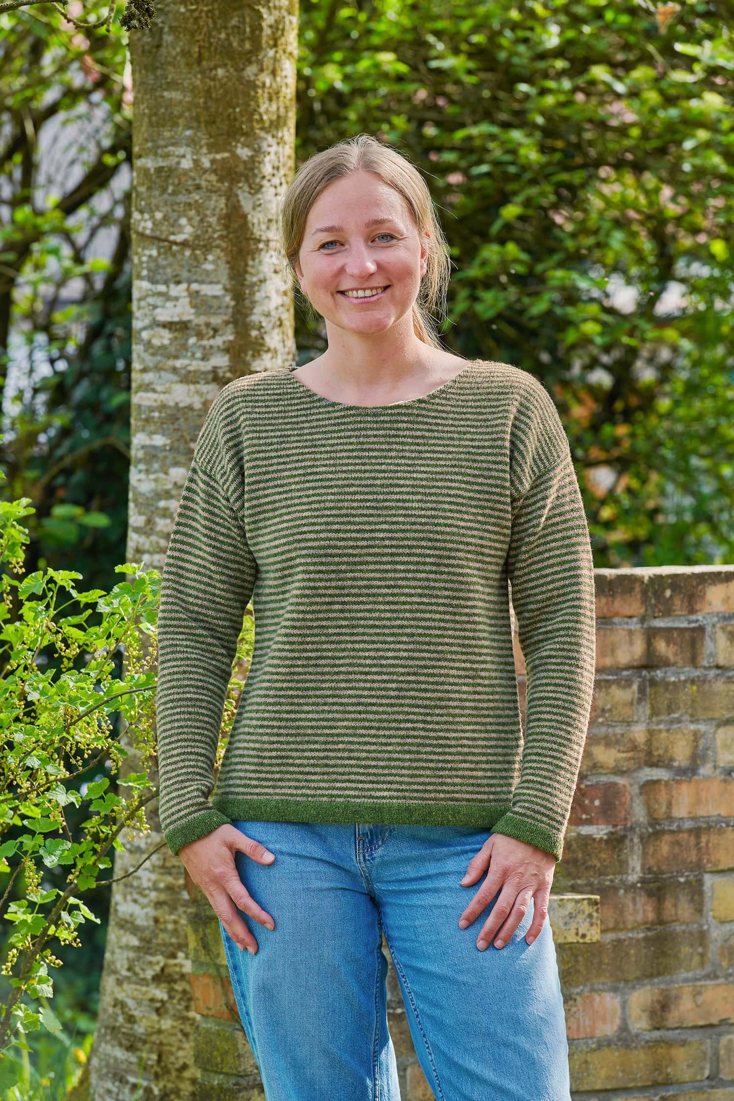 Frau mit Jeans trägt einen grün geringelten Pullover vom Finkhof aus Bio-Schurwolle