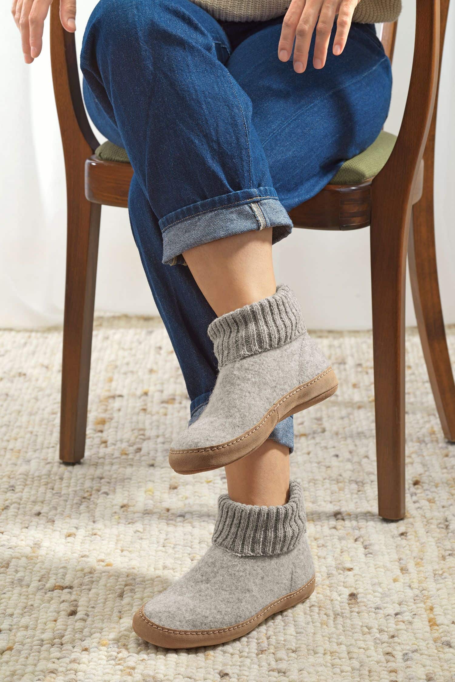 Person trägt hellgraue Finkhof Hüttenschuhe aus bio Wolle (kbT) mit einer Sohle aus pflanzlich gegerbtem Rindsleder