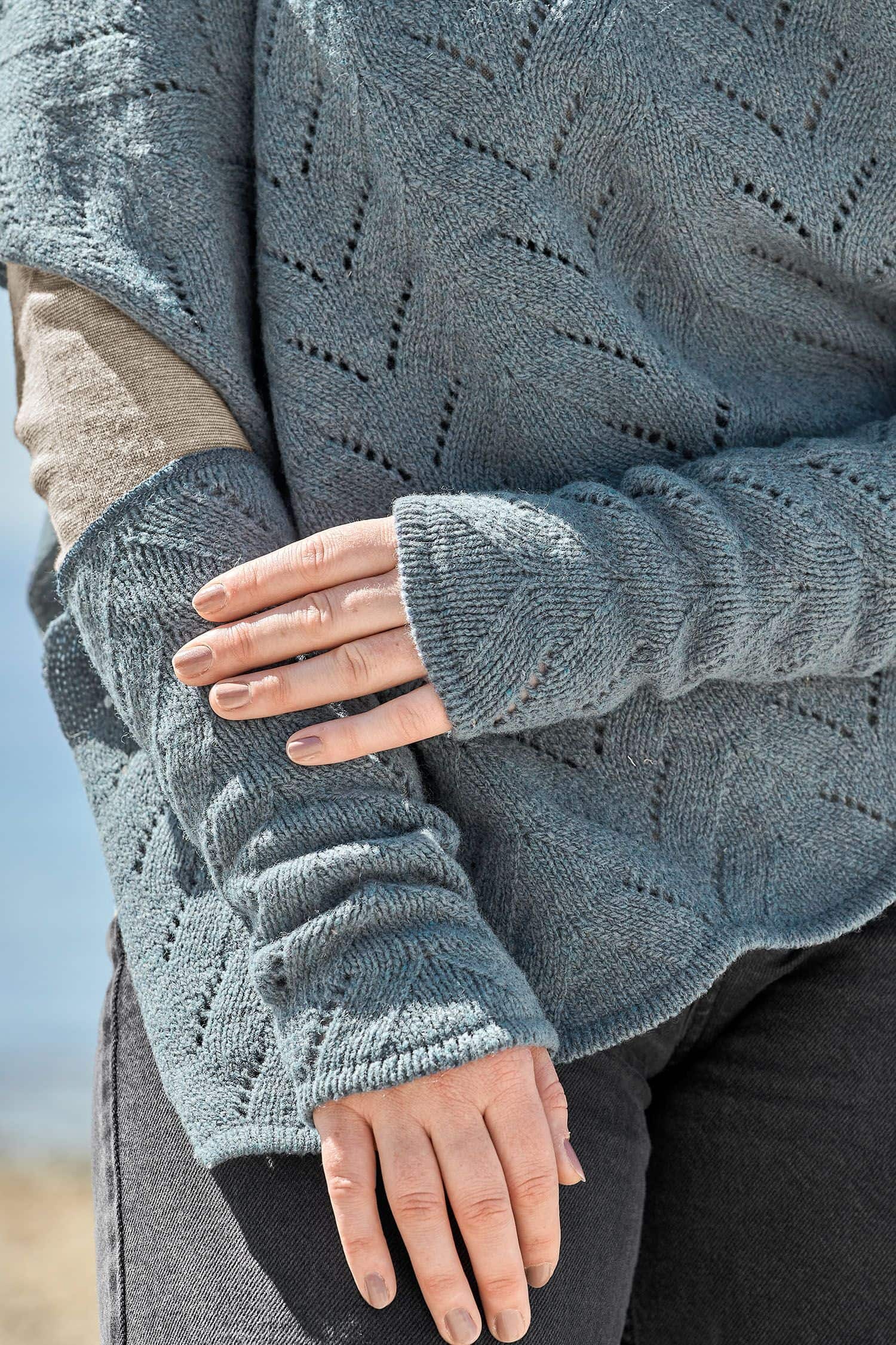 Detailaufnahme der rauchblauen Armstulpen und des Ponchos mit Ajourmuster vom Finkhof aus bio Wolle (kbT)